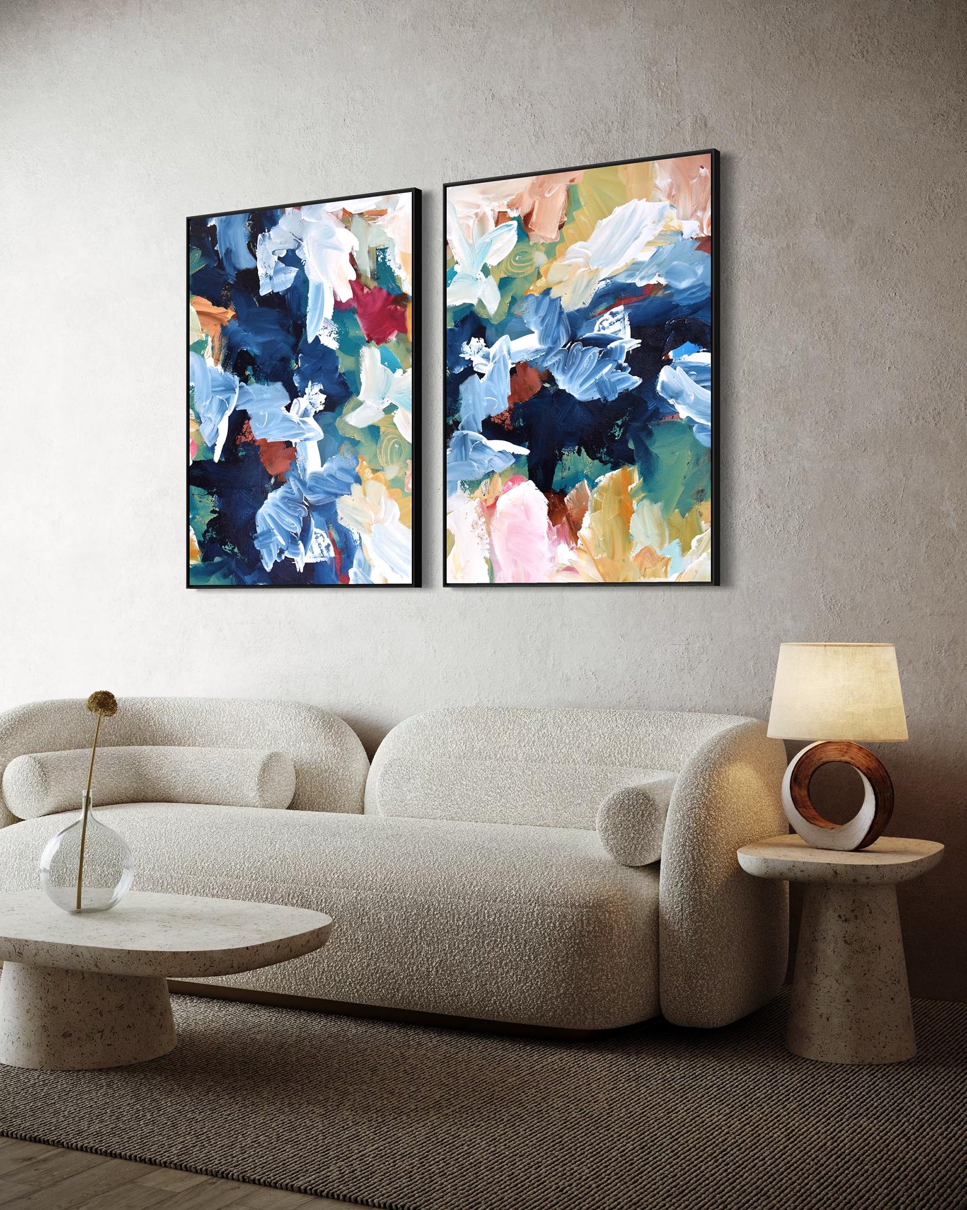 Two abstract paintings on a wall above a sofa with side tables.