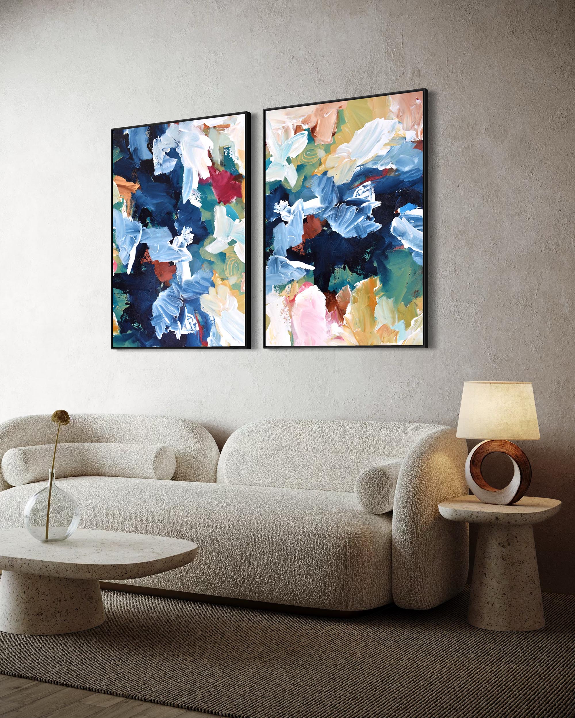 Two abstract paintings on a wall above a sofa with side tables.