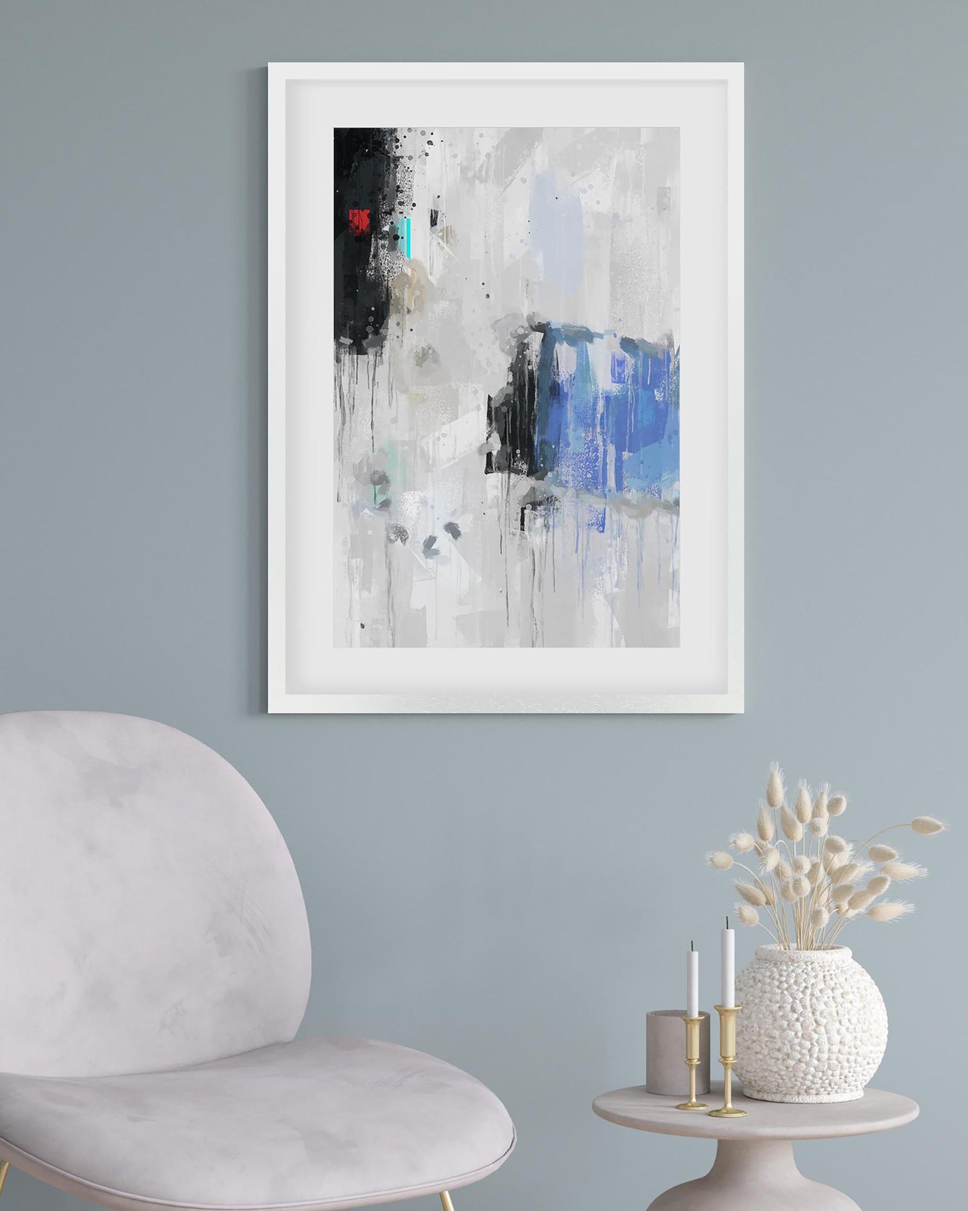 Abstract art print on a wall with a chair and decorative items below.