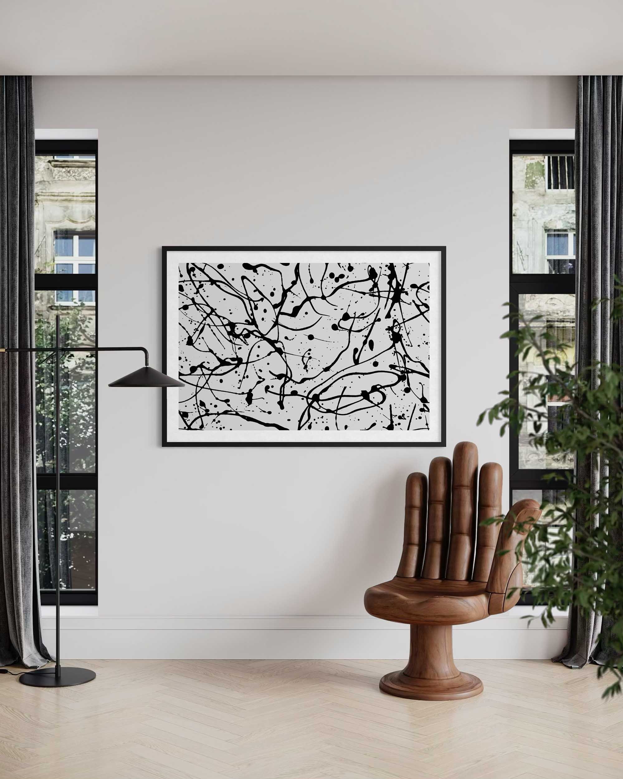 Abstract black and white artwork on a wall in a modern living room with a wooden chair and plant.