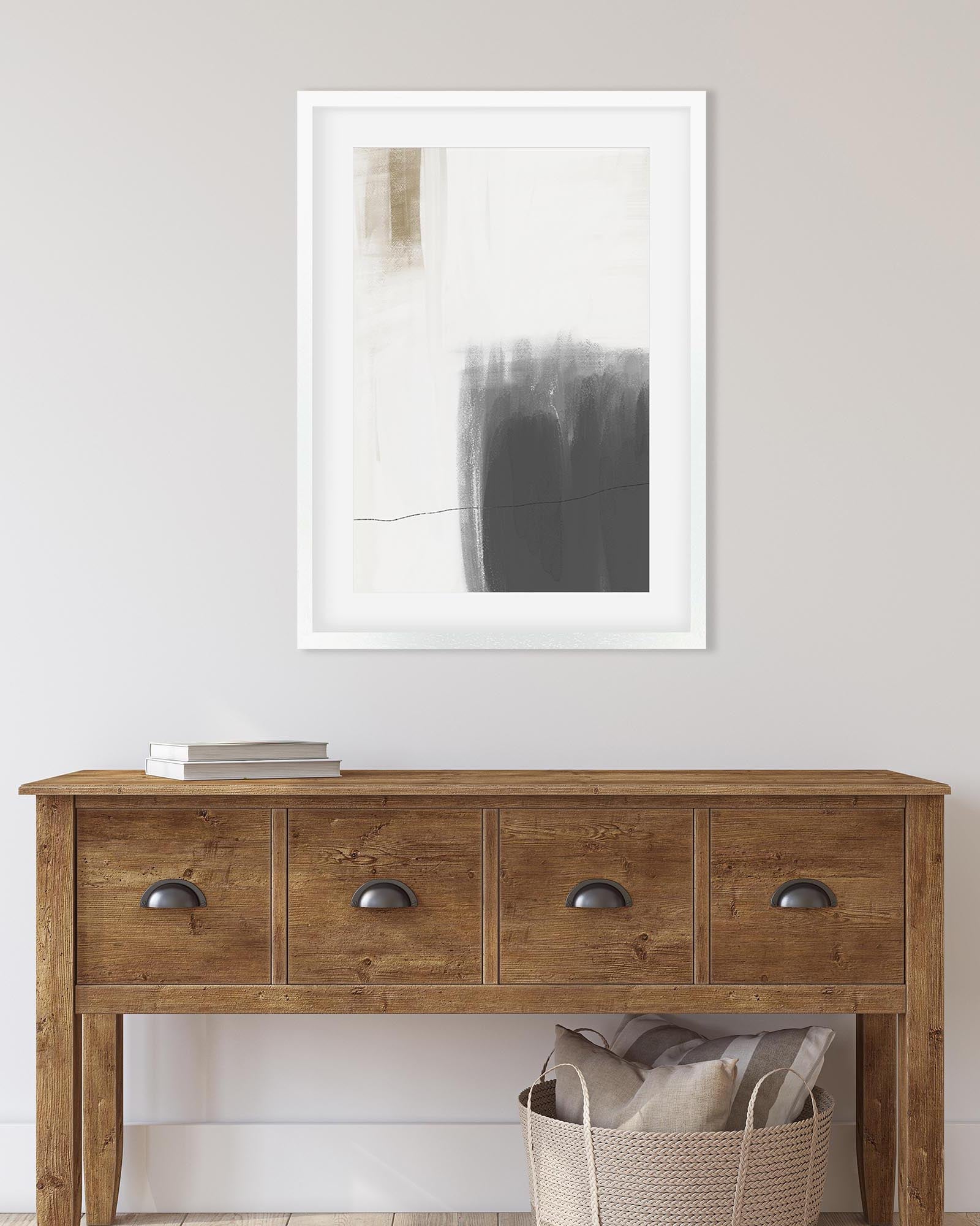 Wooden console table with a framed abstract painting on a white wall.