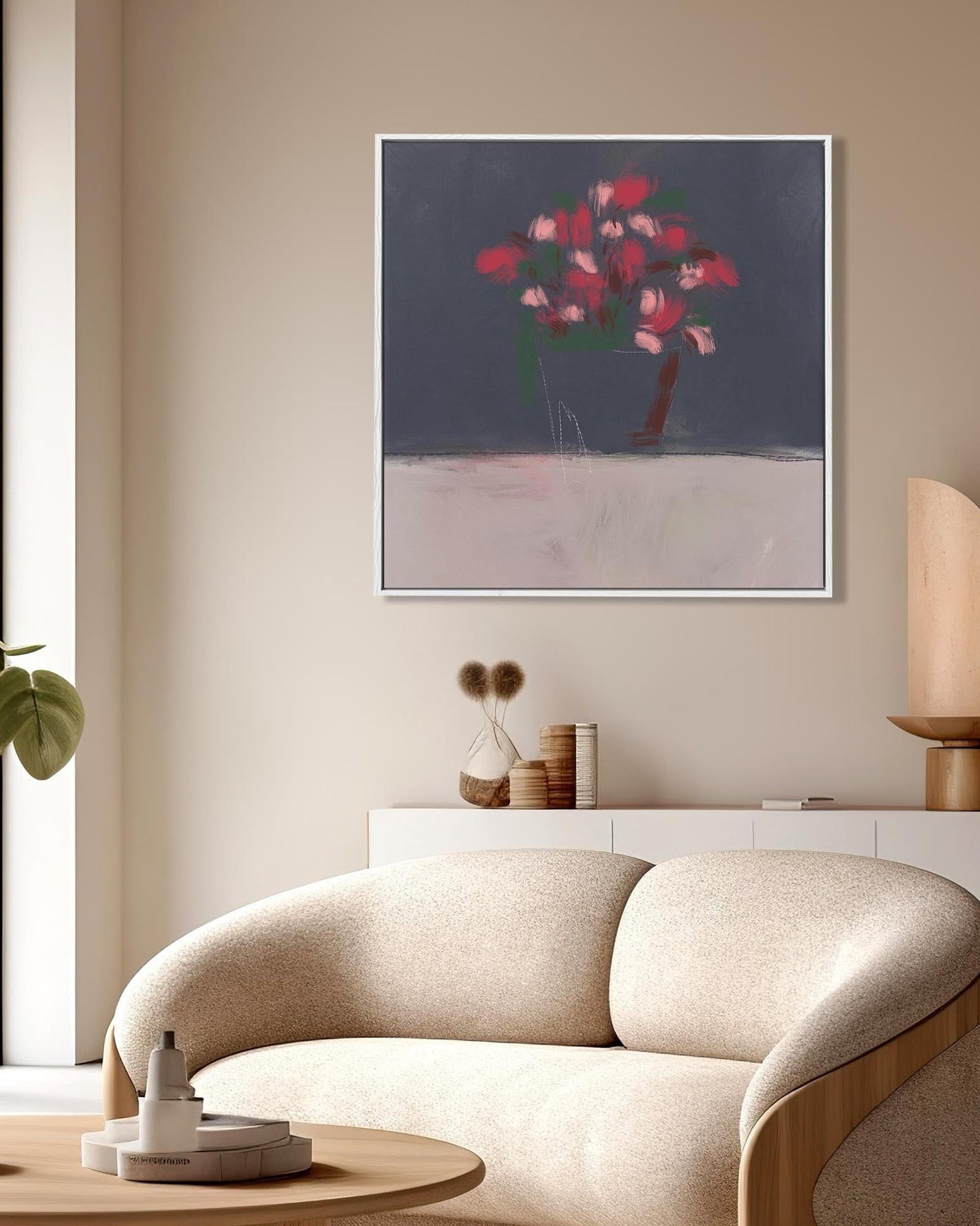 Modern living room with a beige sofa, round wooden table, and abstract artwork on the wall.