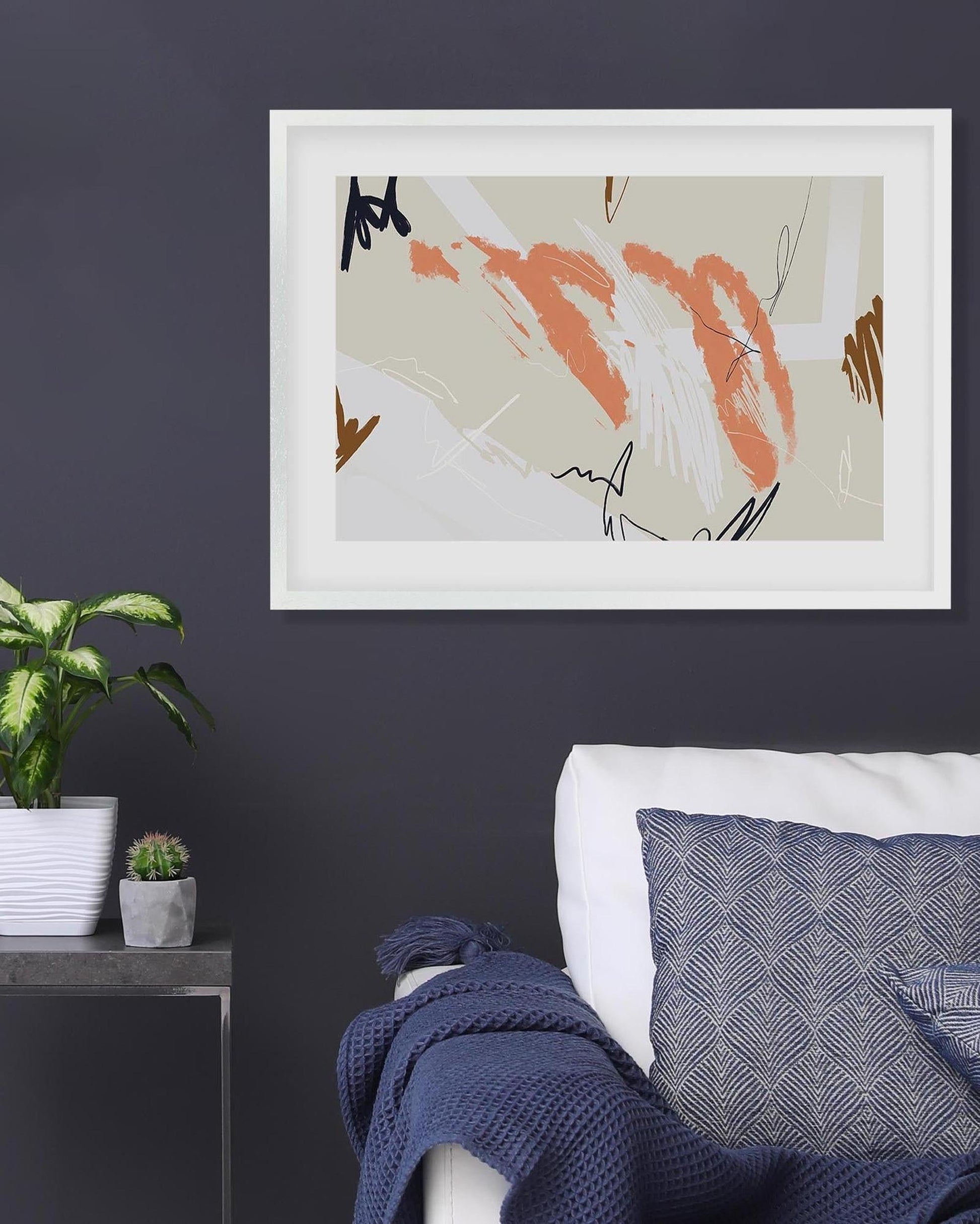 Framed abstract art piece on a dark wall above a sofa with decorative pillows.