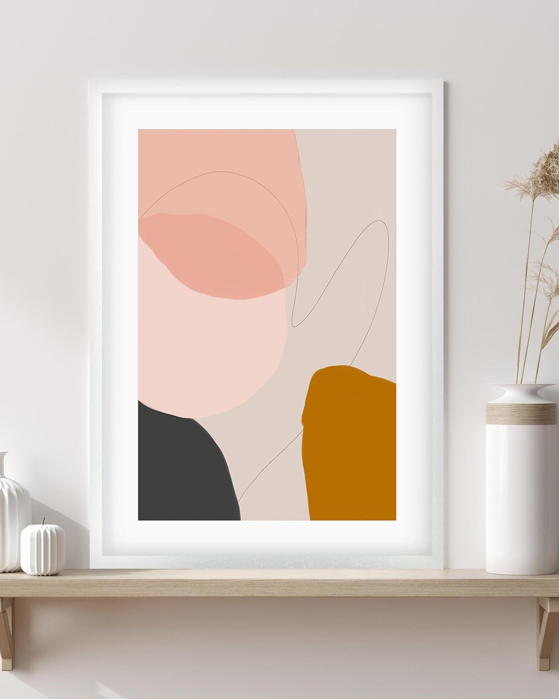 Framed abstract art print with geometric shapes on a wall above a wooden shelf.