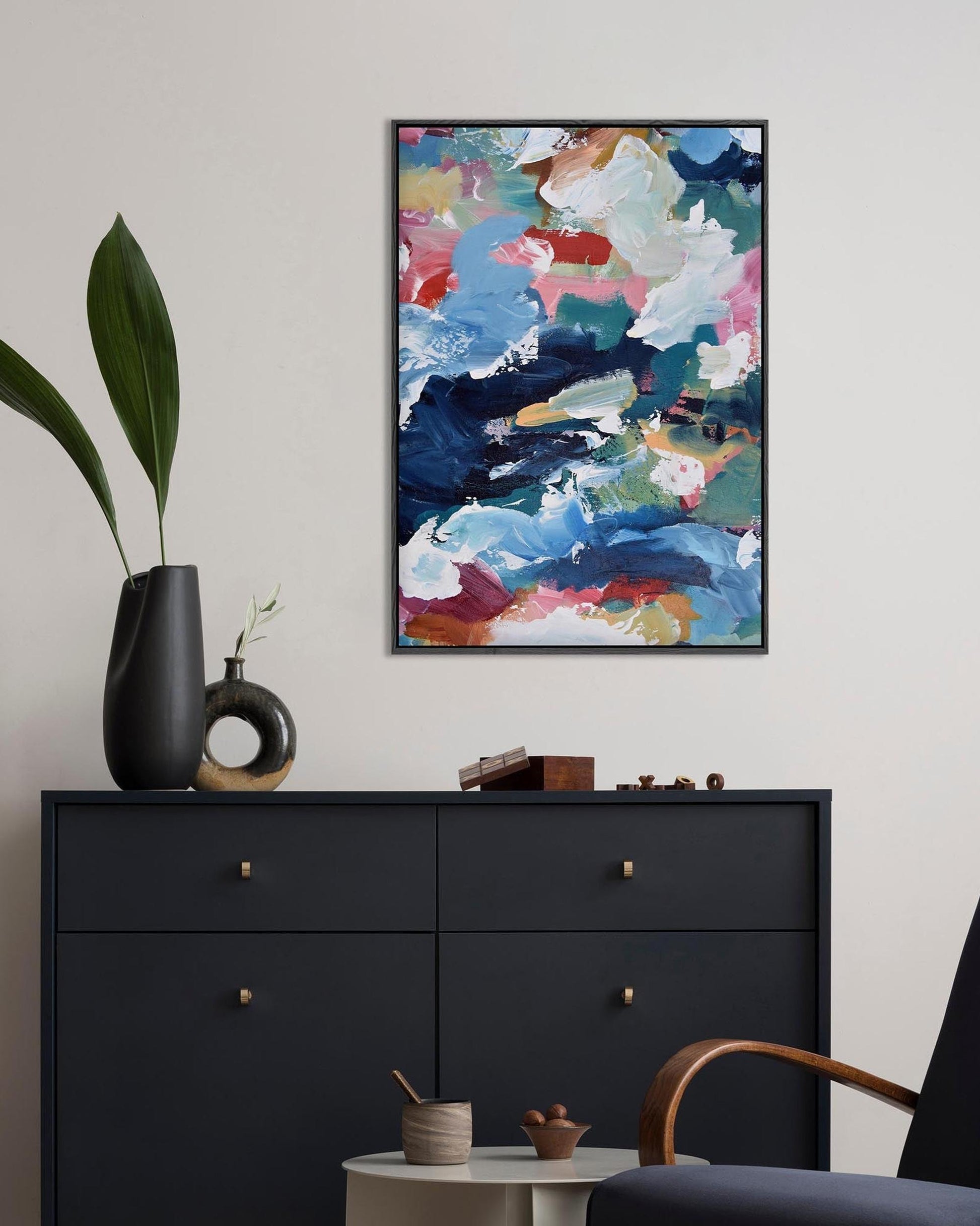Modern interior with a black dresser, abstract painting, and decorative items.