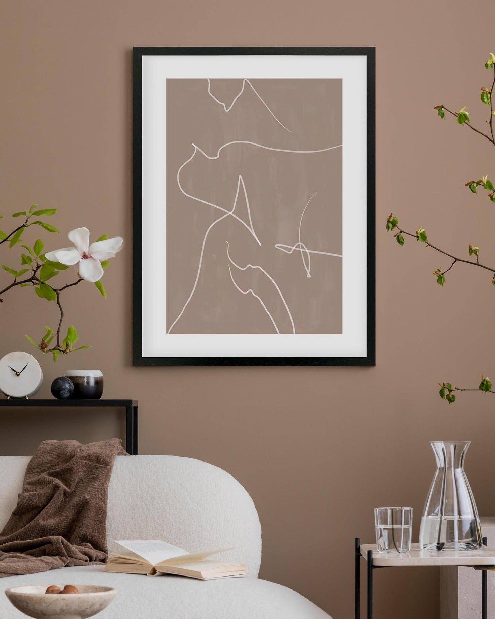 Framed abstract line art on a wall with a sofa and decorative items in a room.