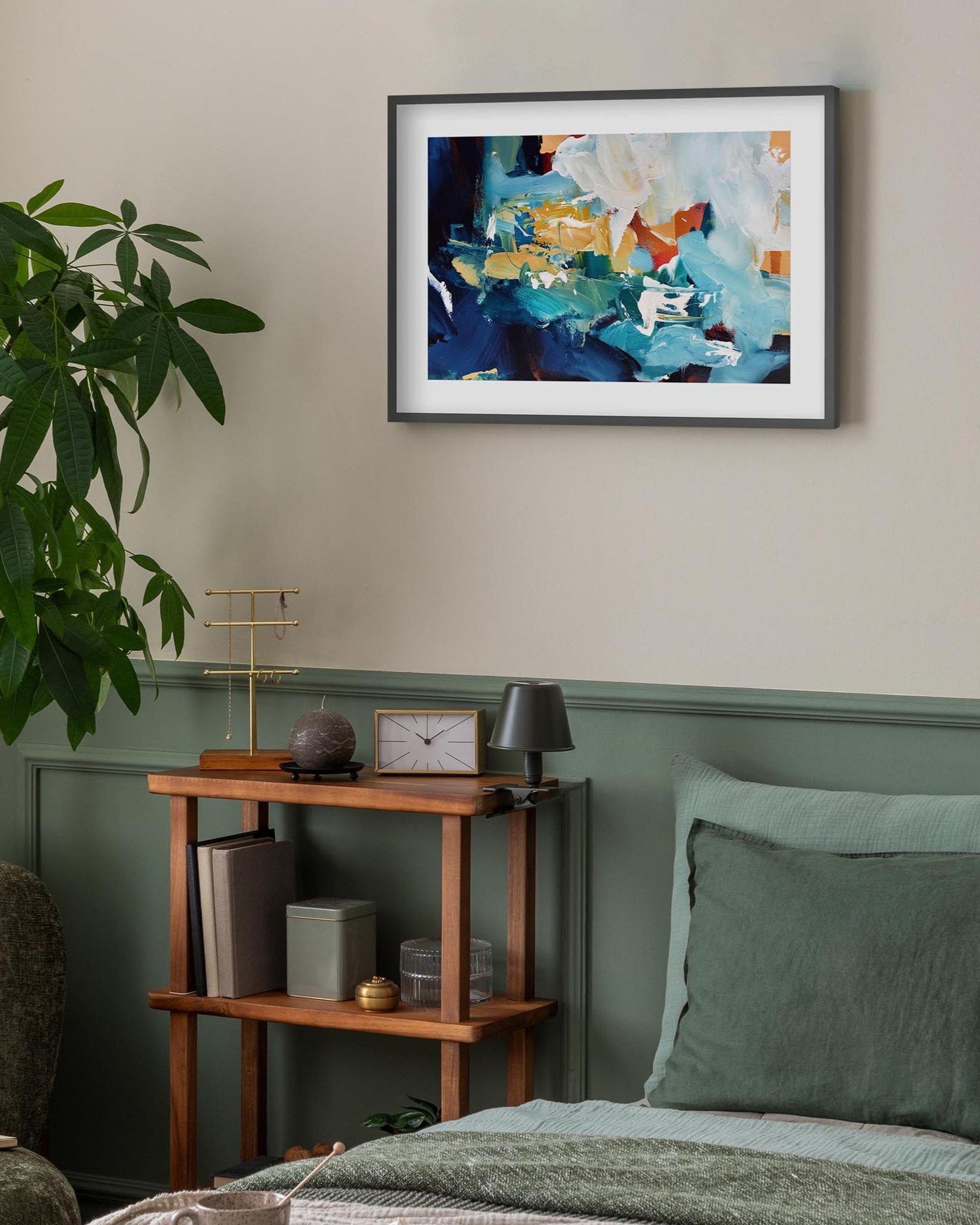 Framed abstract painting on a wall above a wooden shelf with decorative items.