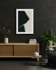 Framed abstract art piece on a dark wall with wooden furniture and decor.