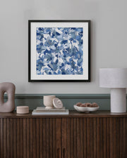 Framed abstract blue and white pattern on a wall above a wooden console table.