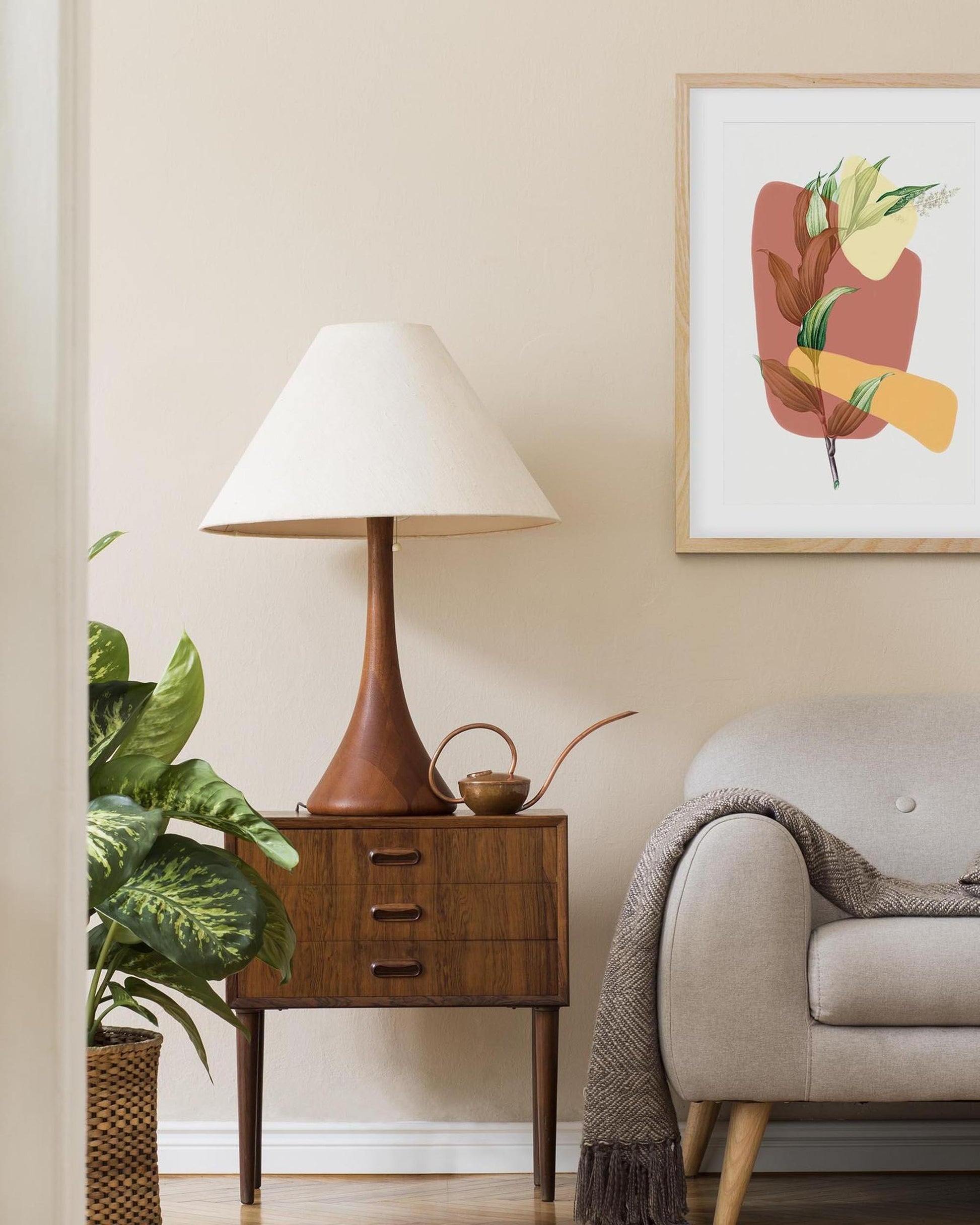 Living room with a wooden side table, lamp, and sofa against a beige wall with a framed abstract art piece.