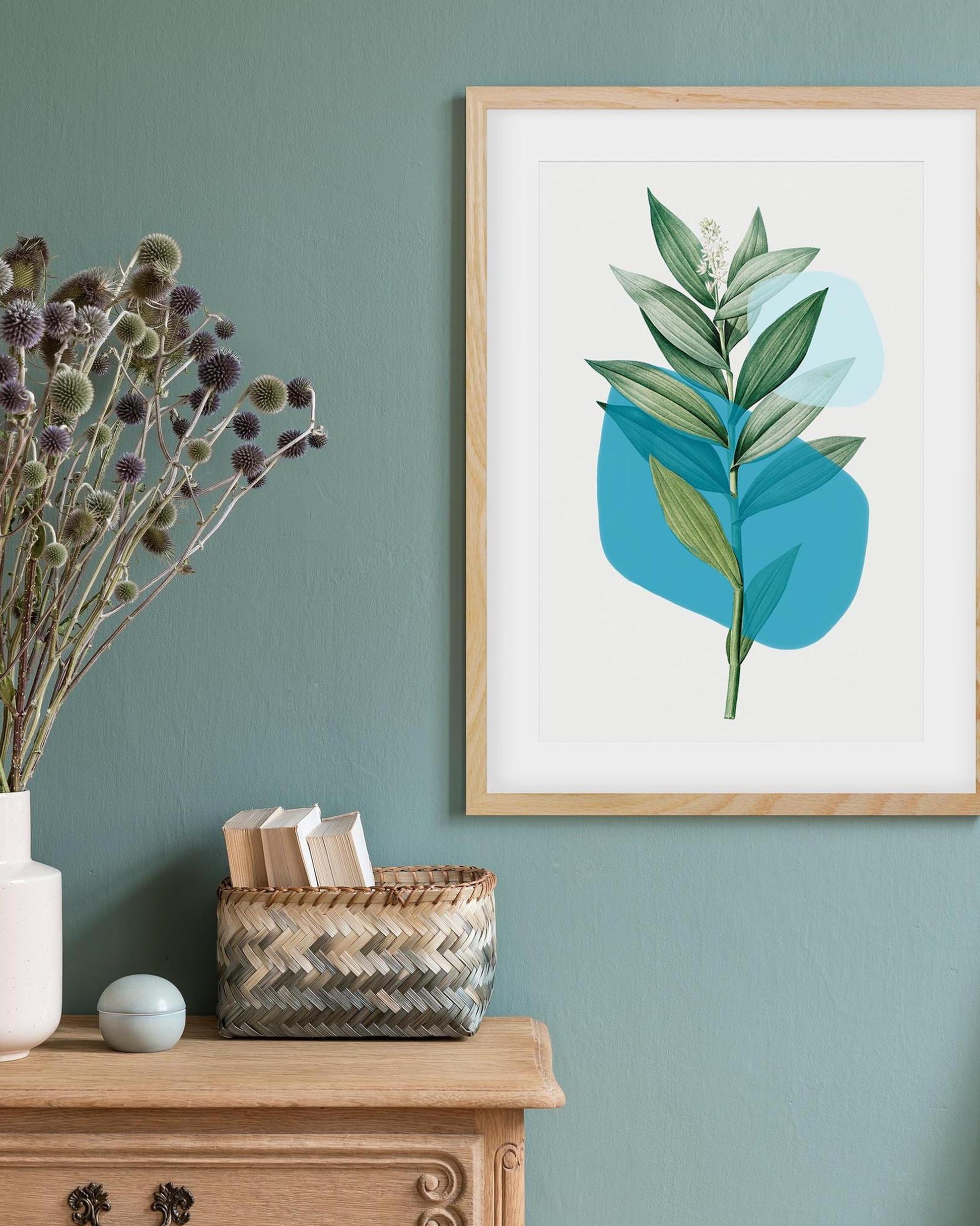 Framed botanical art print on a wall with decorative items below.