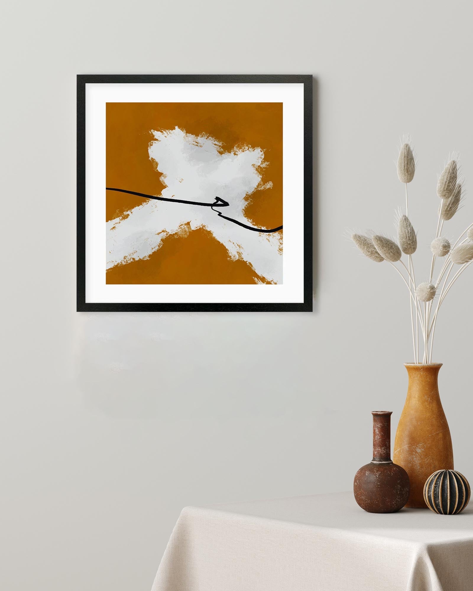 Framed abstract art piece on a wall with decorative vases on a table below.