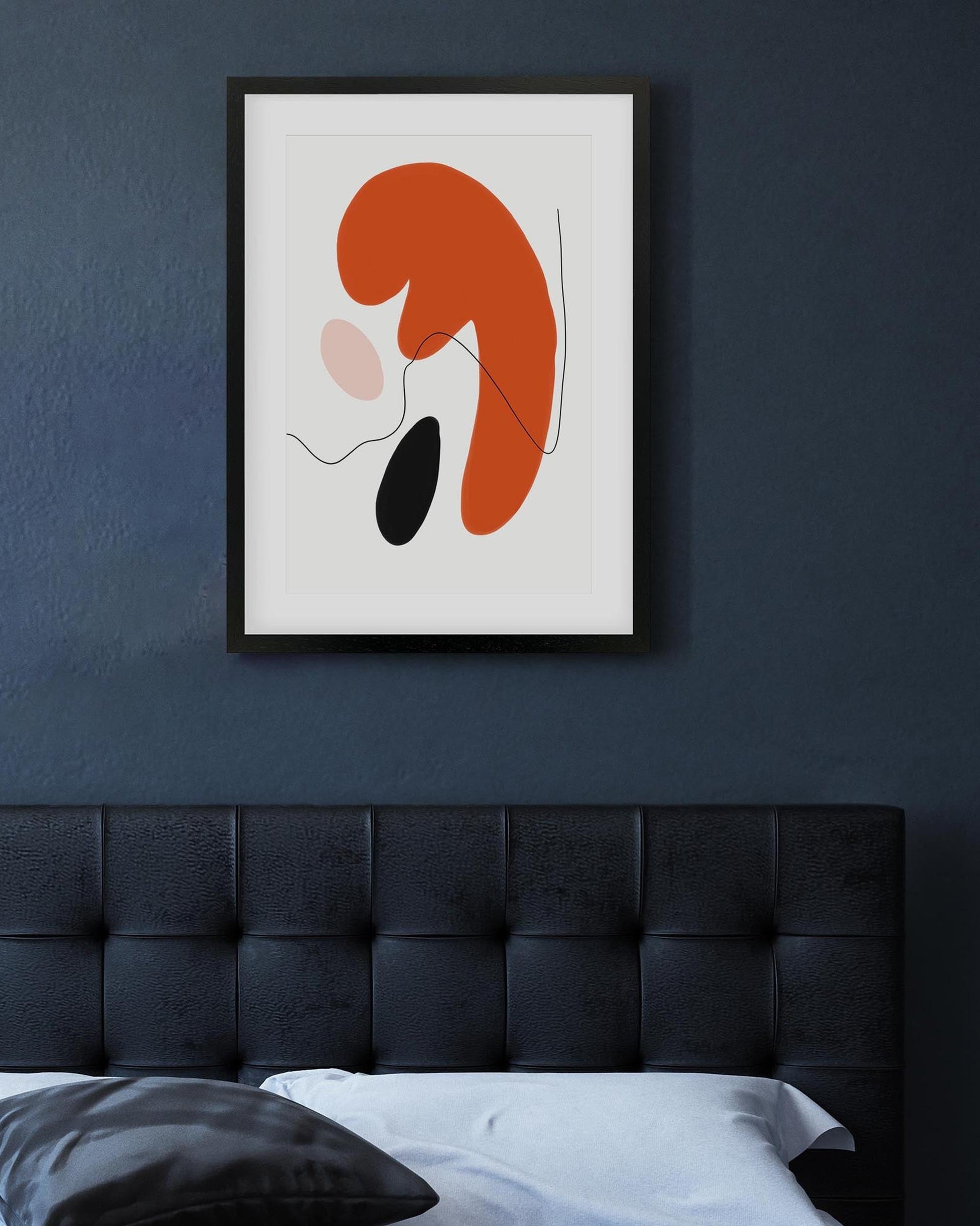 Abstract art print on a dark wall above a bed
