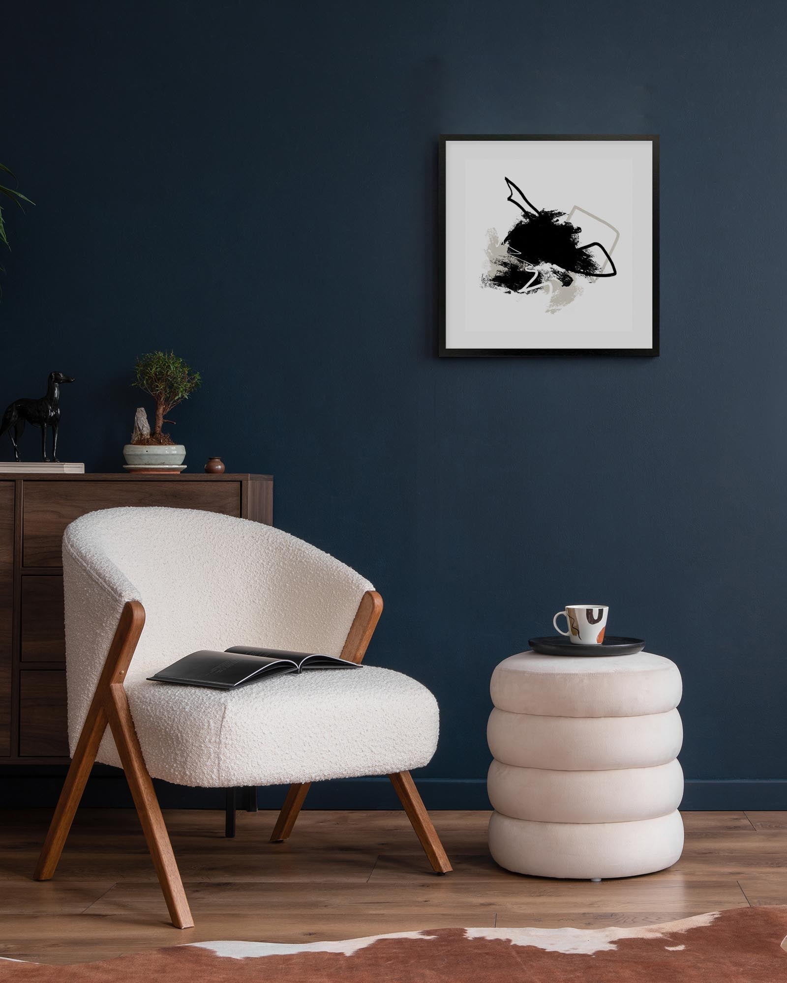 Modern living room with a white armchair, side table, and abstract art on the wall.