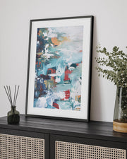 abstract art print in a black frame on a sideboard 