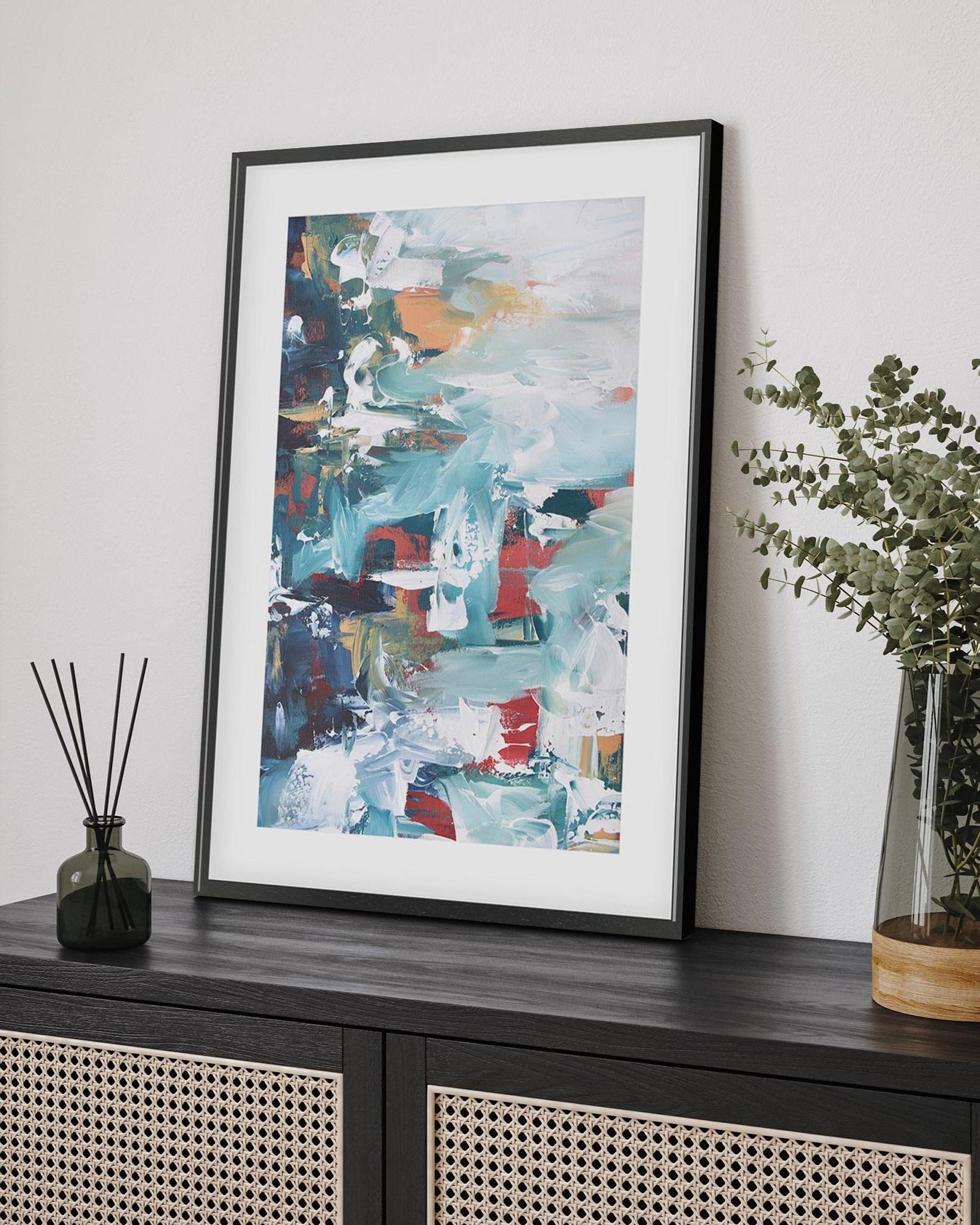 abstract art print in a black frame on a sideboard 