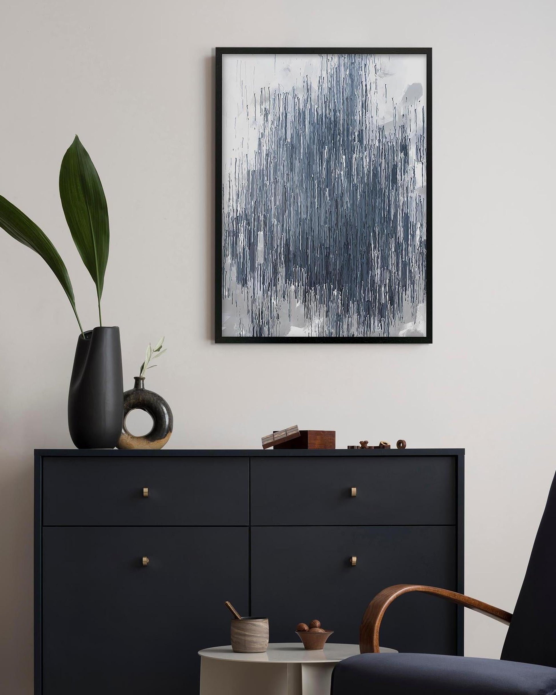 Black dresser with decorative items and abstract art on a white wall
