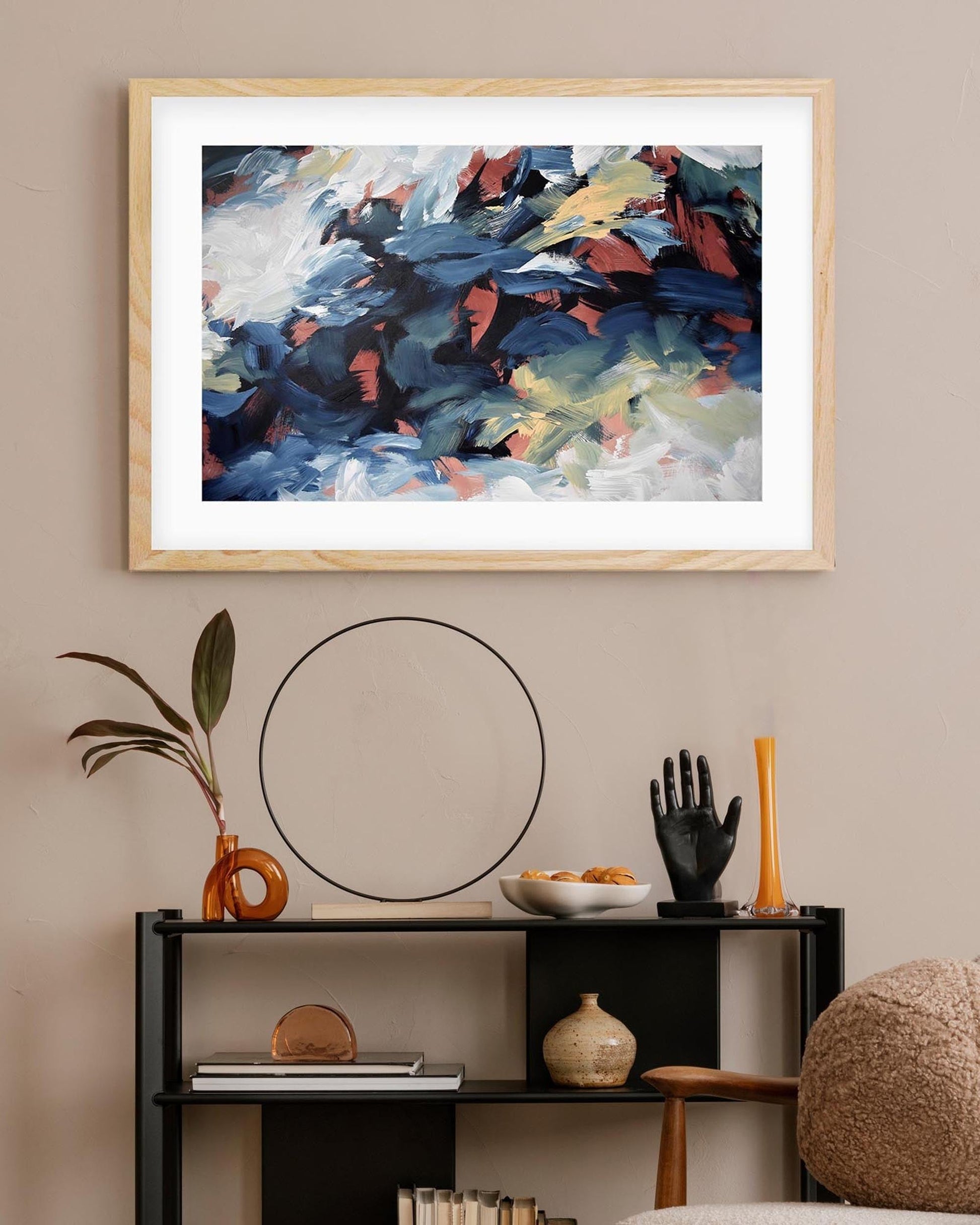 Framed abstract painting on a wall above a console table with decorative items.