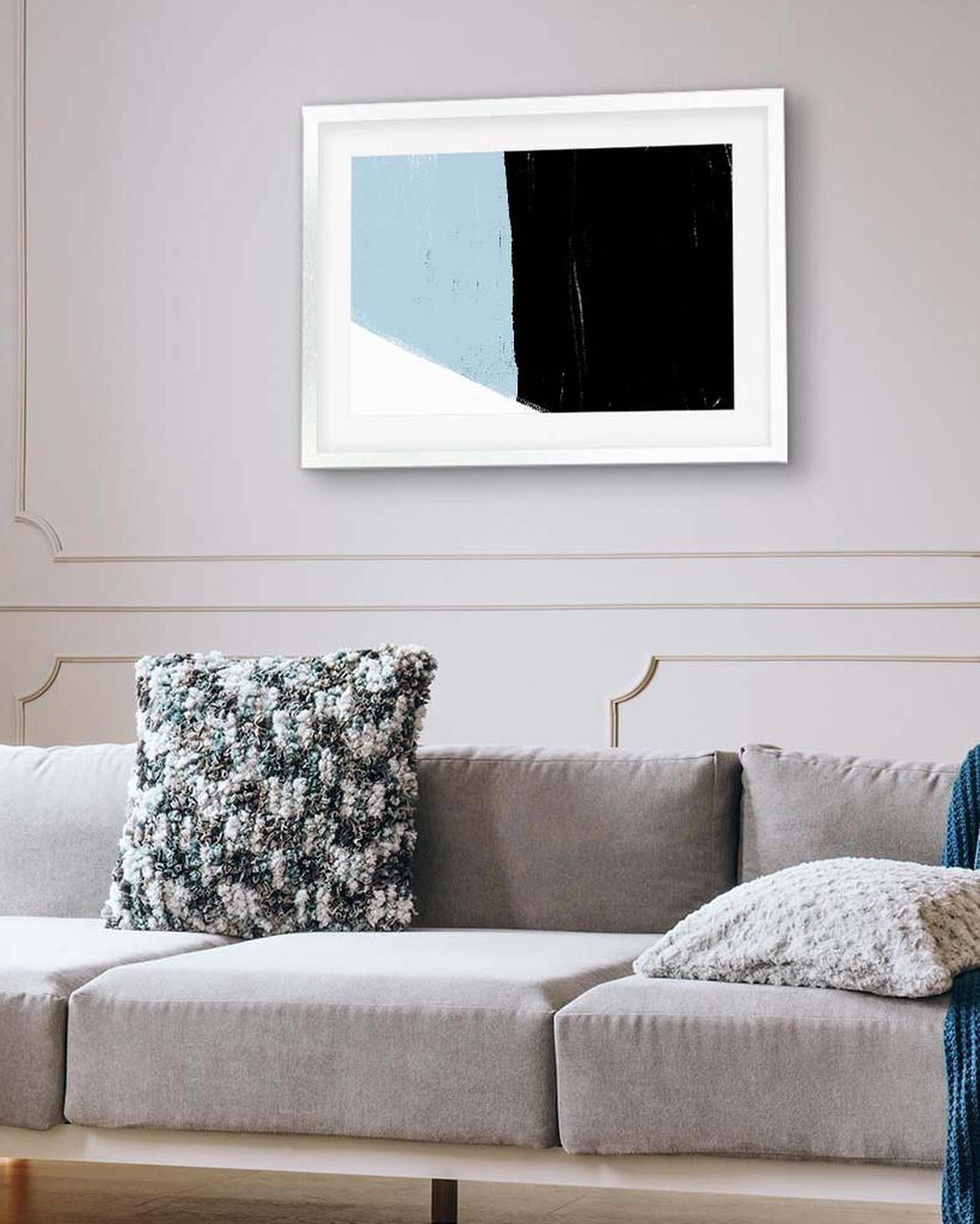 Framed abstract art piece on a wall above a sofa with decorative pillows.