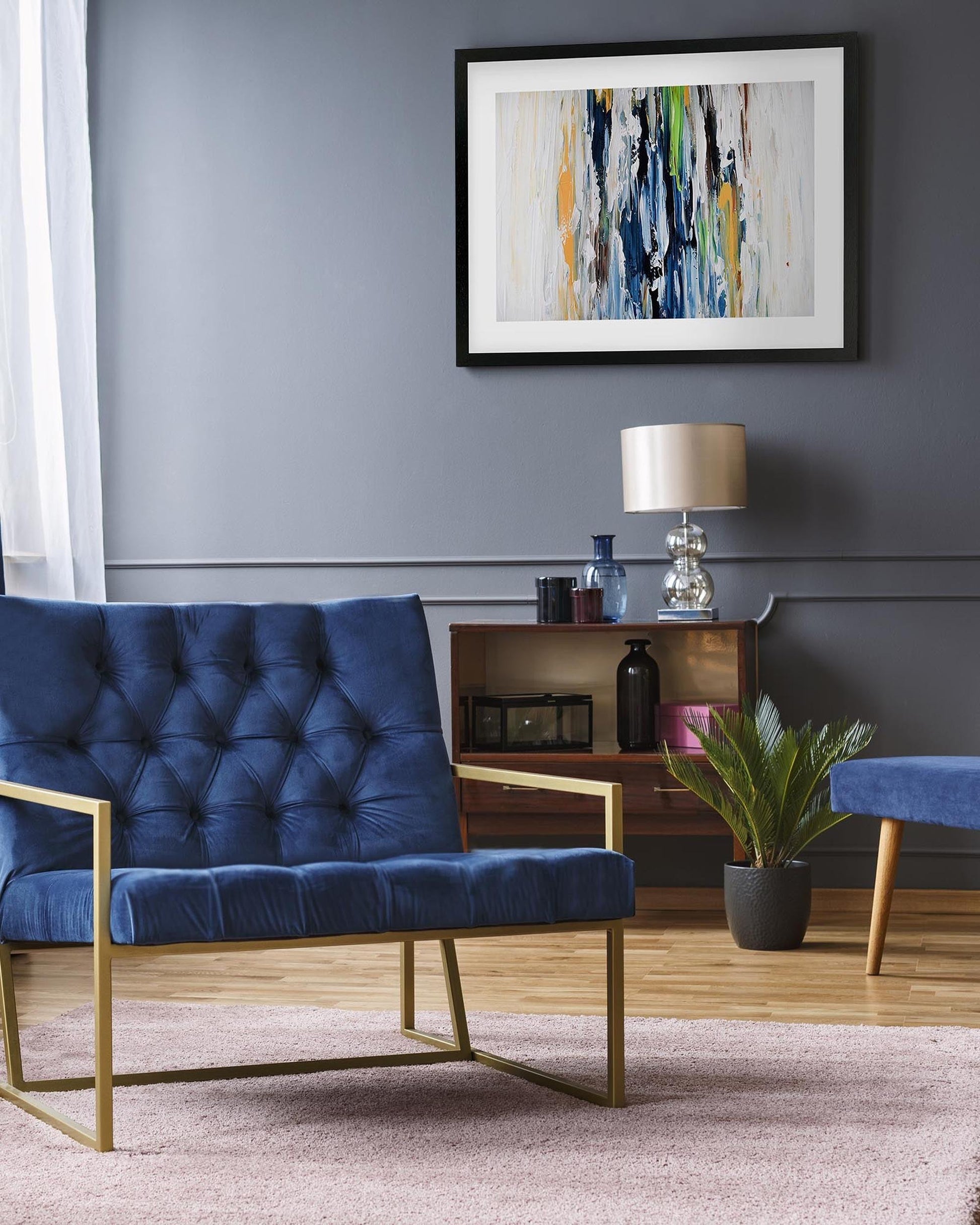 Modern living room with a blue tufted sofa, wooden side table, and abstract art on the wall.