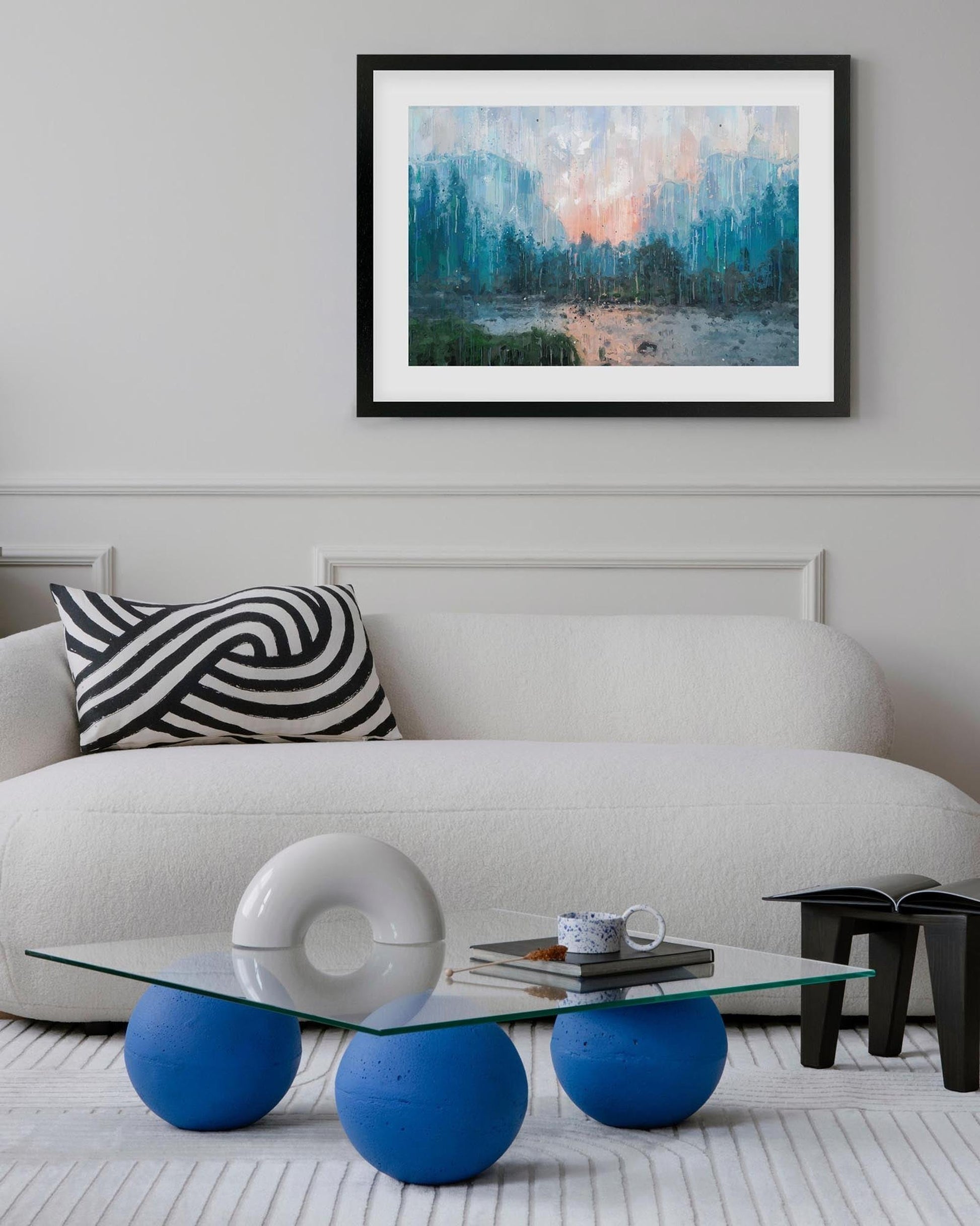 Modern living room with a white sofa, blue coffee table, and abstract painting on the wall.