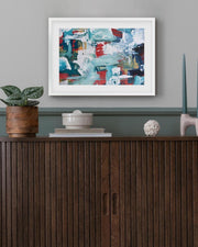 Abstract painting on a wall above a wooden cabinet with decorative items.