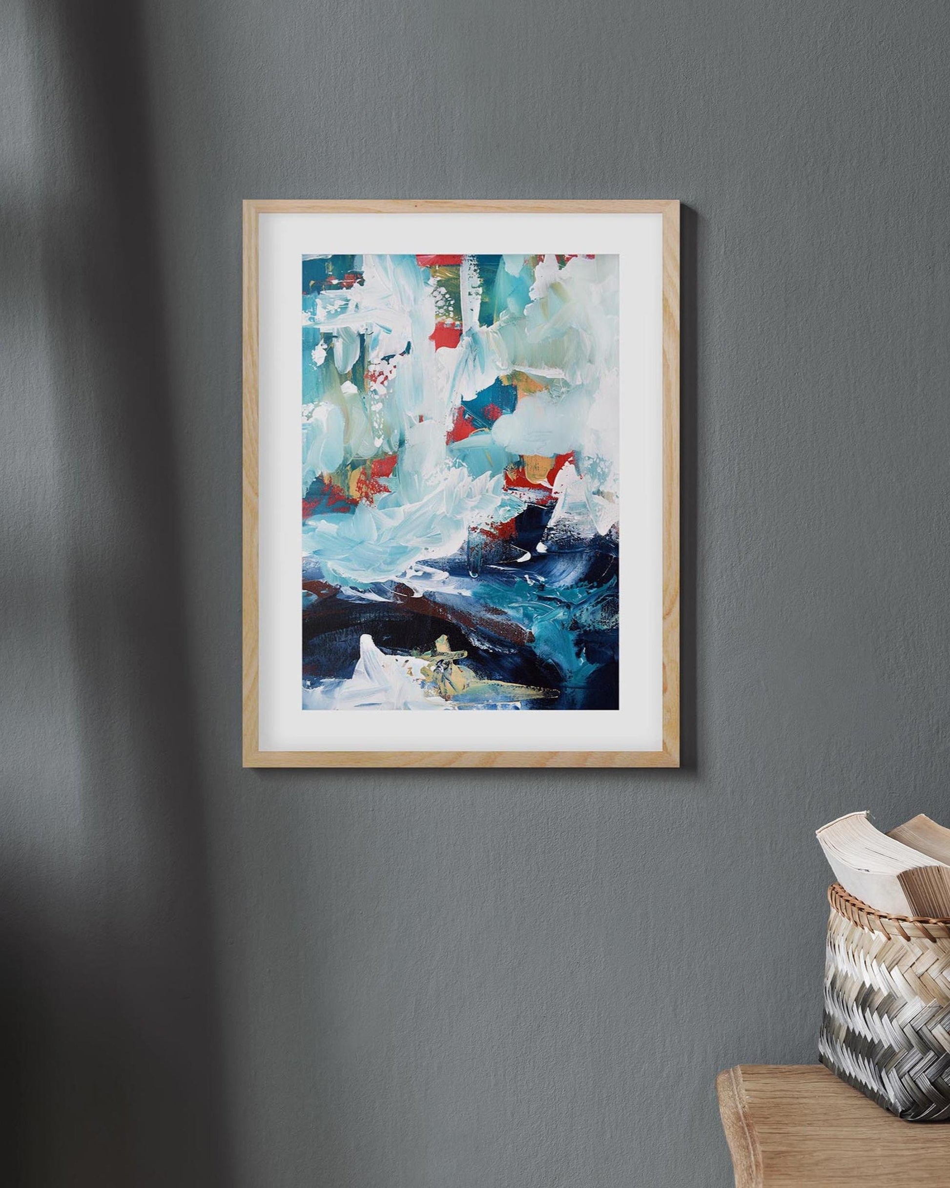Framed abstract painting on a gray wall with wooden ladder and basket in the corner.