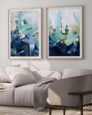 Two abstract art pieces in gold frames on a wall above a sofa.