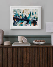 Framed abstract art on a wall above a wooden console table with decorative items.