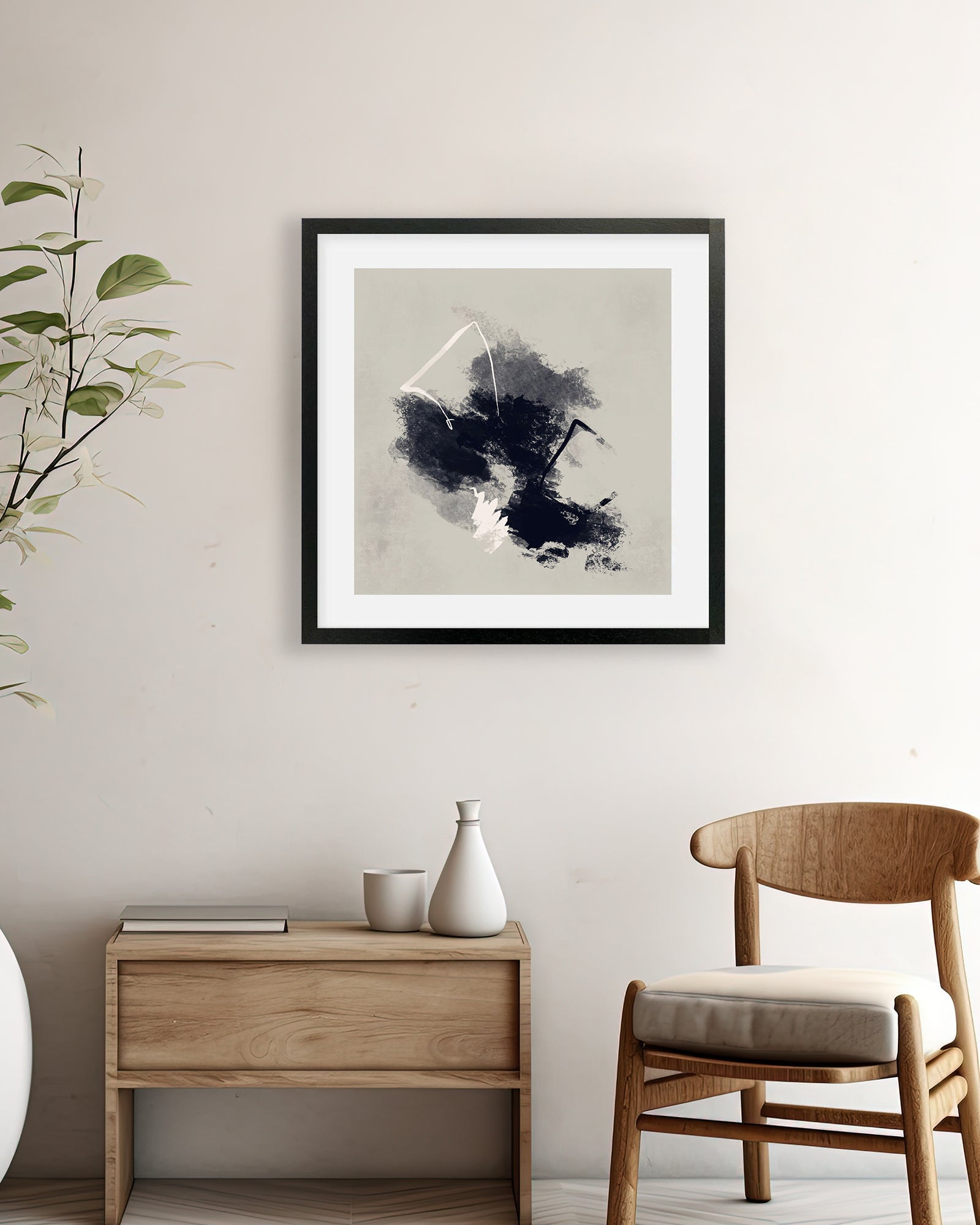 Framed abstract art piece on a wall above a wooden side table with a vase and books, next to a wooden chair.