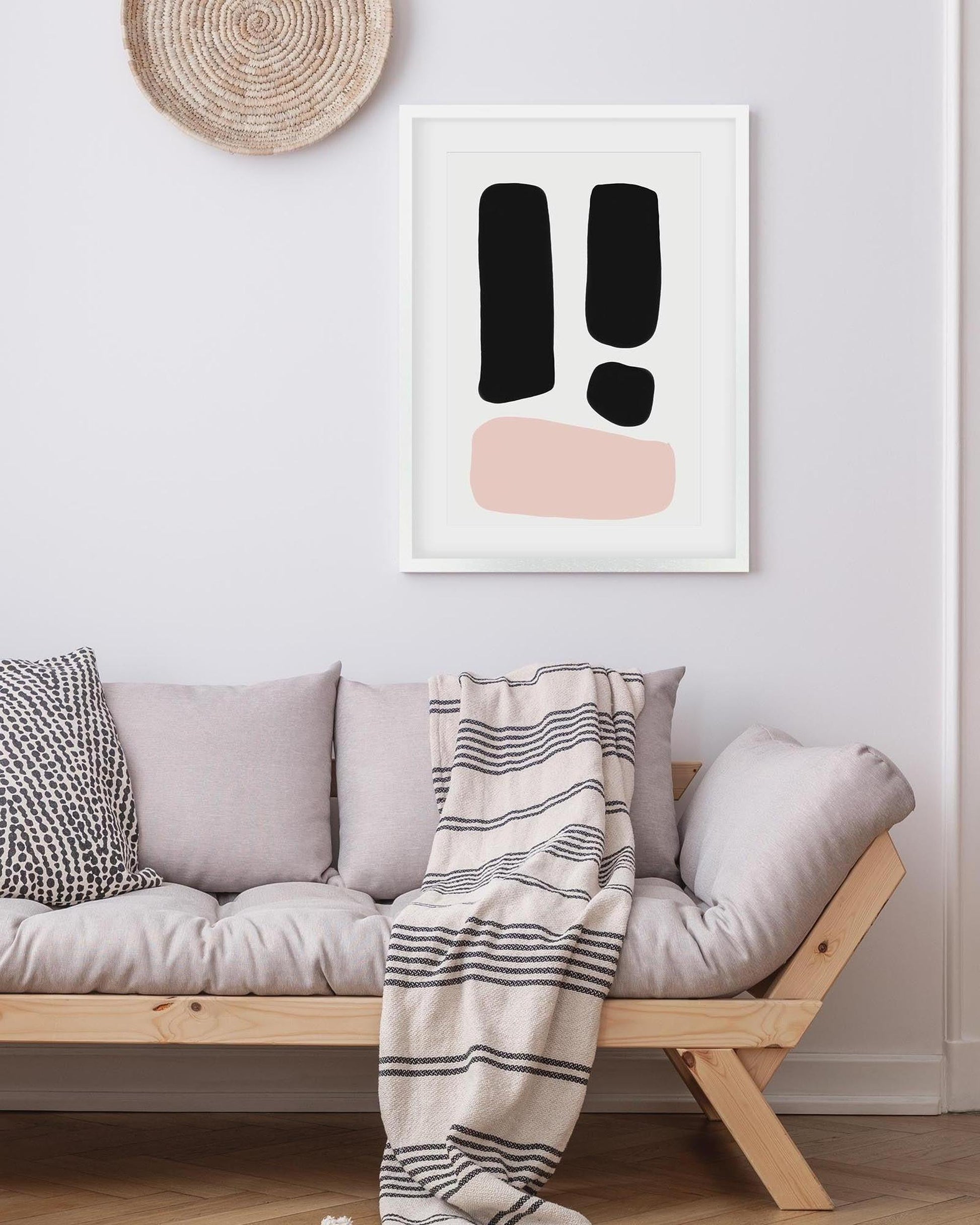 Modern living room with a sofa, striped blanket, and abstract art on the wall.