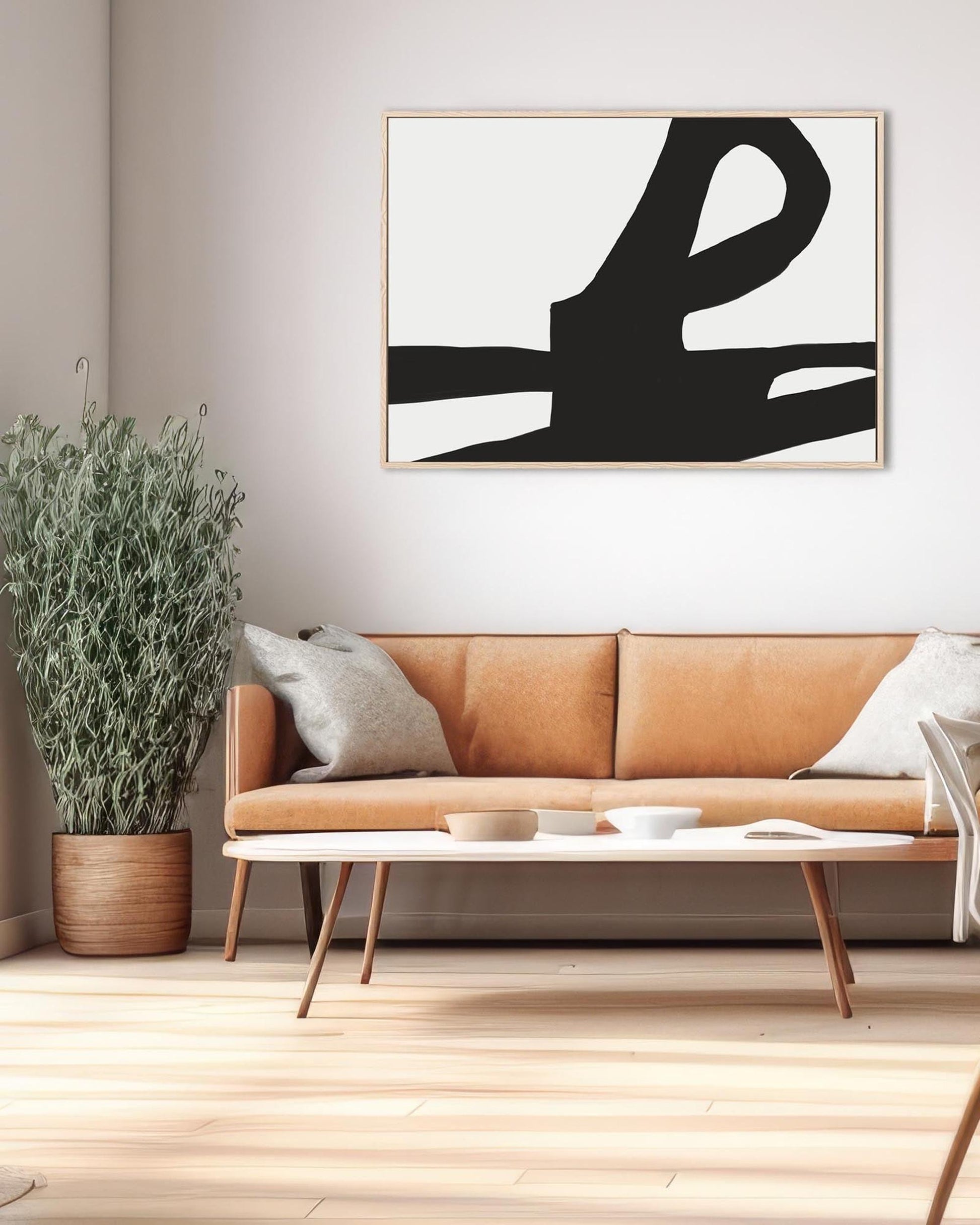 Modern living room with a tan sofa, abstract art, and potted plant.