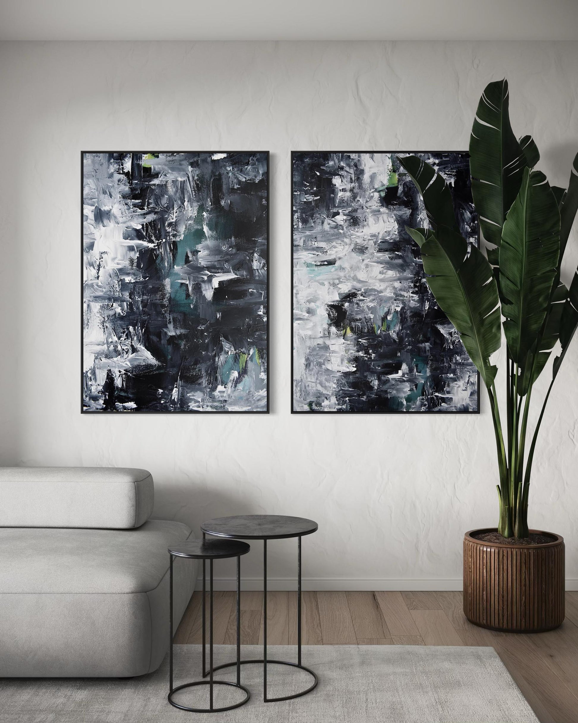 Two abstract paintings on a wall above a sofa with a plant and side tables in the foreground.