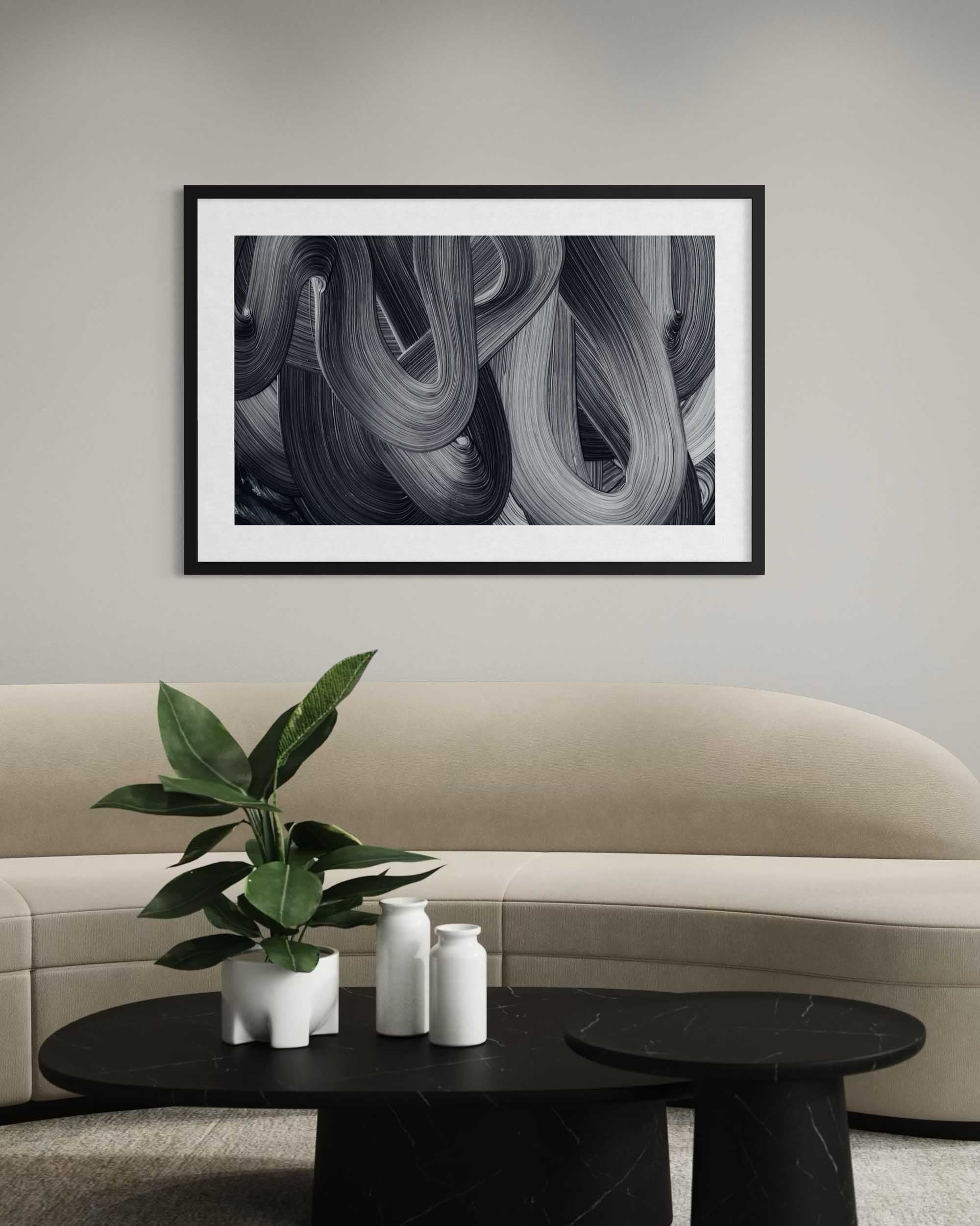 Framed abstract art above a beige sofa with a coffee table and plant