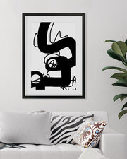 Framed abstract black and white artwork on a wall above a sofa with decorative pillows.