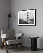 Modern interior with a chair, side table, and framed picture of a bridge on a gray wall.