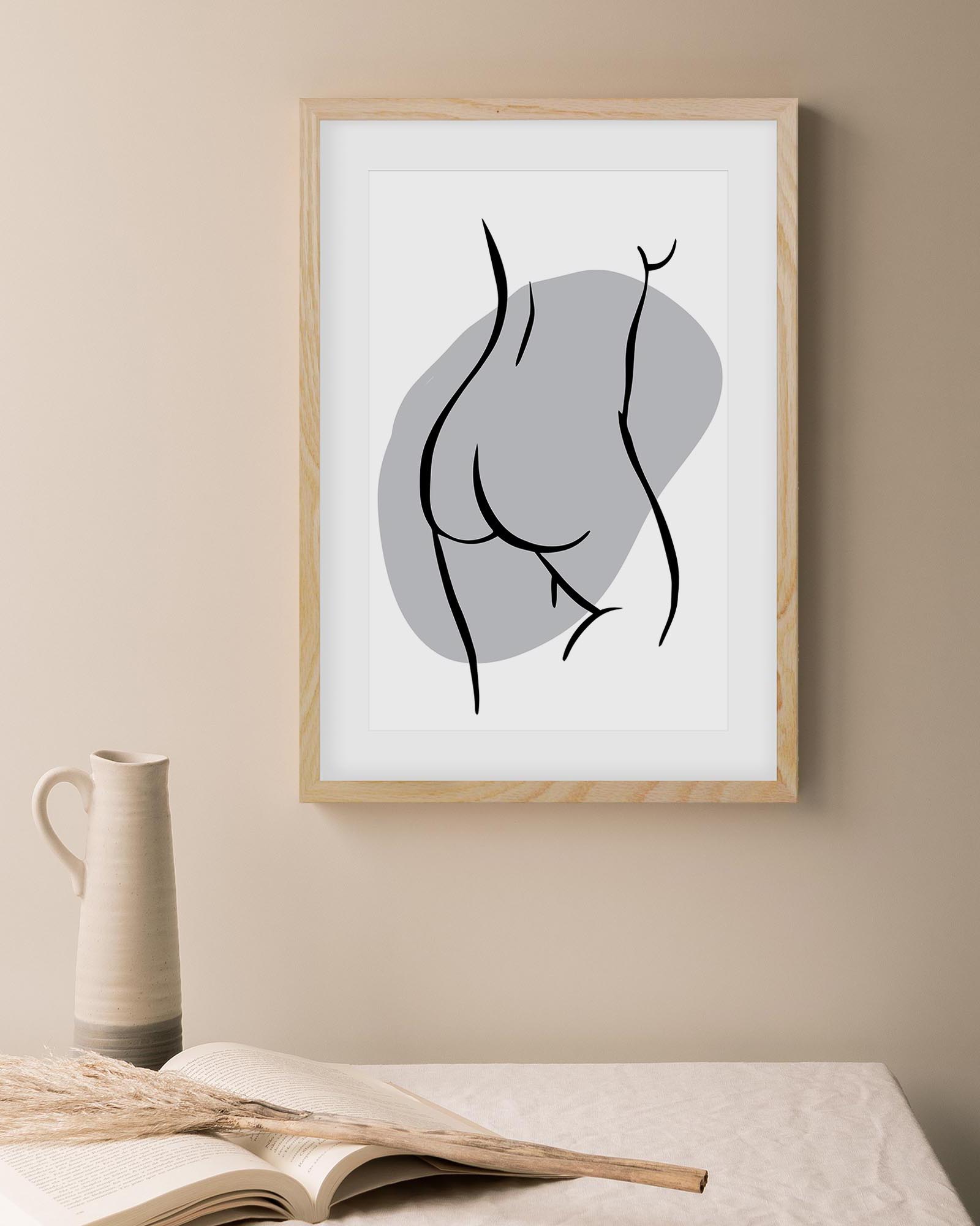 Framed abstract art print on a wall with a vase and book in the foreground.