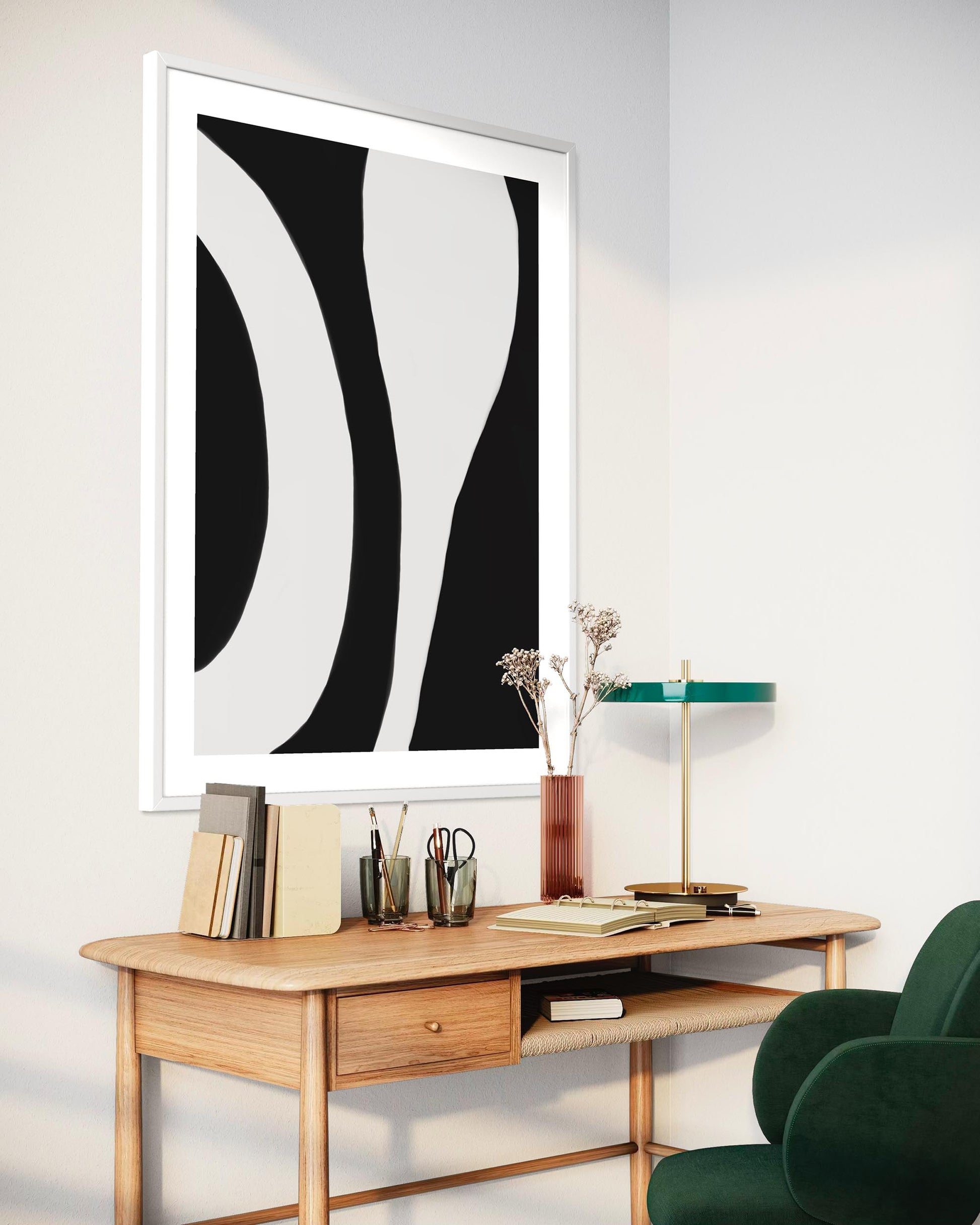 Modern interior with a wooden desk, abstract black and white artwork, and a green chair.