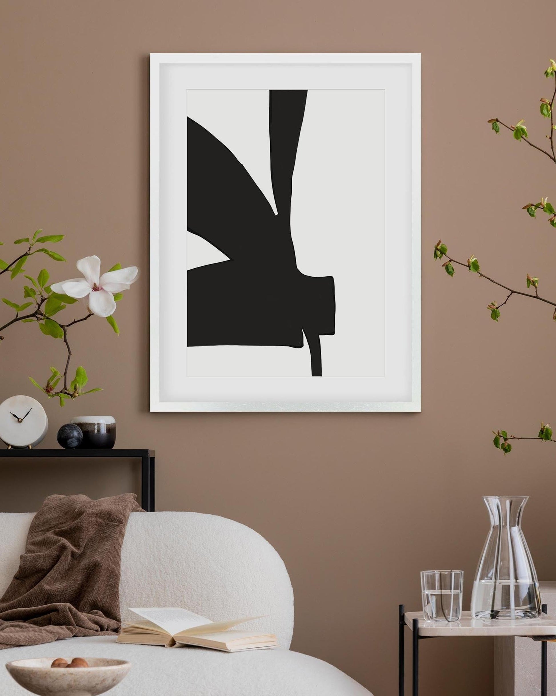 Framed abstract black and white art piece on a brown wall with decorative elements.