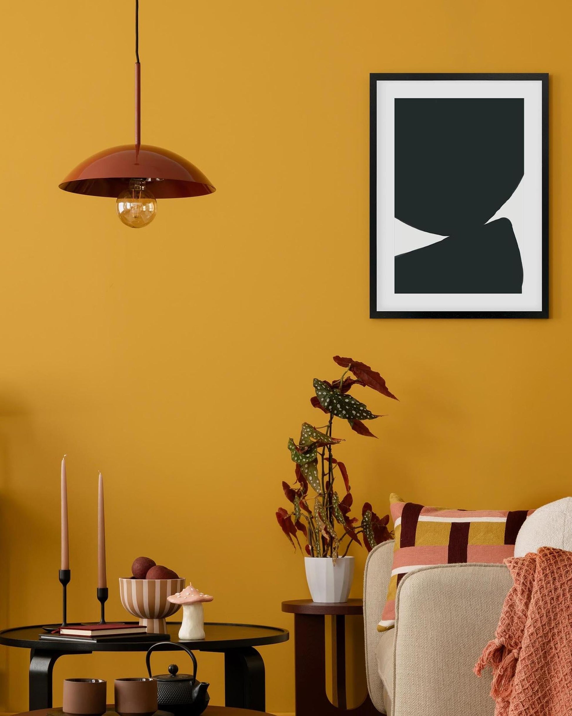 Living room with yellow walls, a black and white abstract art piece, and decorative items.