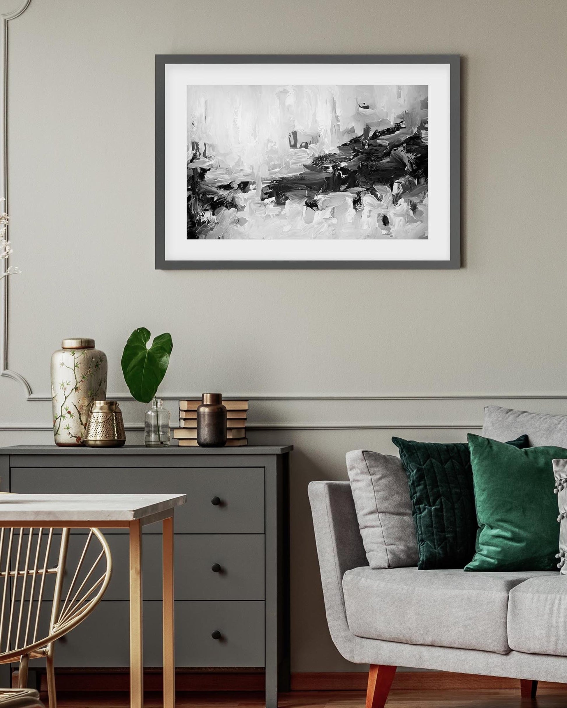 Living room with a gray sofa, decorative pillows, a small table with vases, and a framed abstract art piece on the wall.