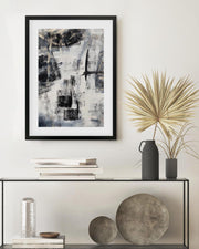 Framed abstract art piece on a wall above a console table with decorative items.