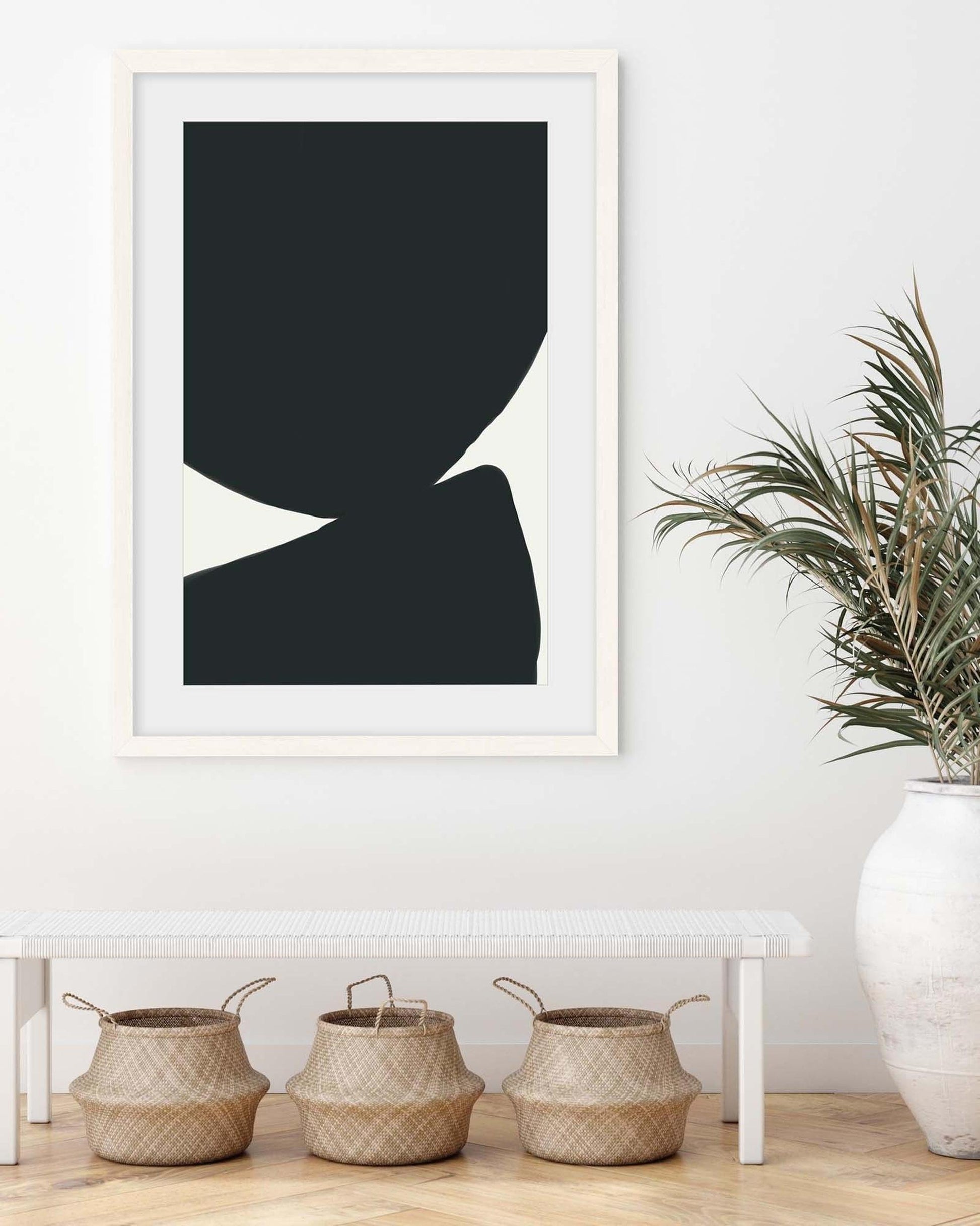 Framed abstract art print on a wall with decorative baskets and a vase below.