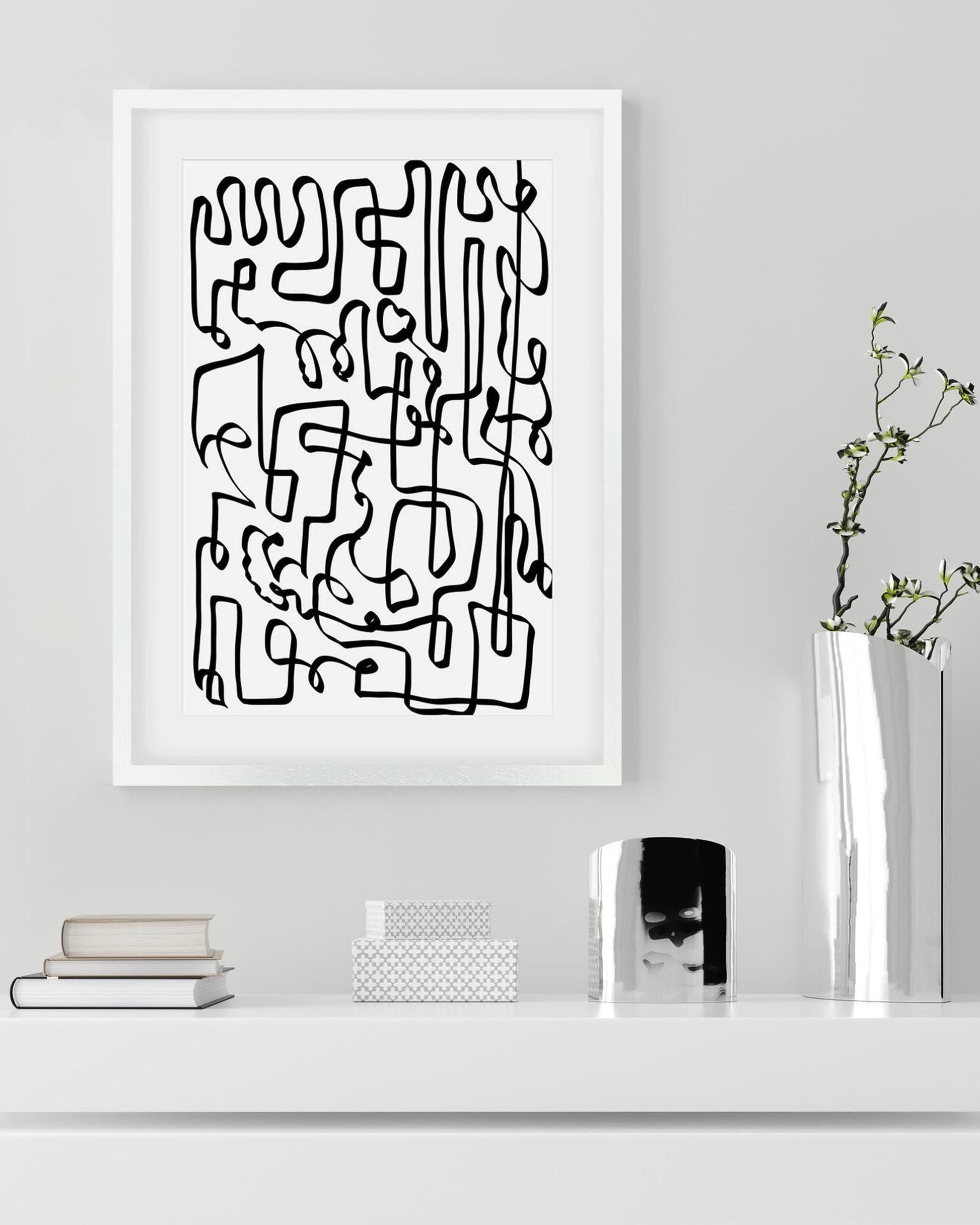 Framed abstract black line art on a white wall with decor items below.