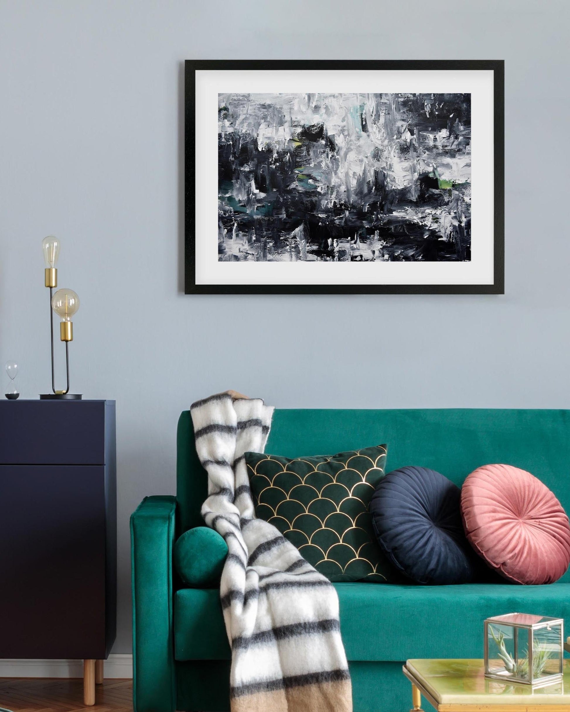 Living room with teal sofa, abstract art on wall, and decorative items.