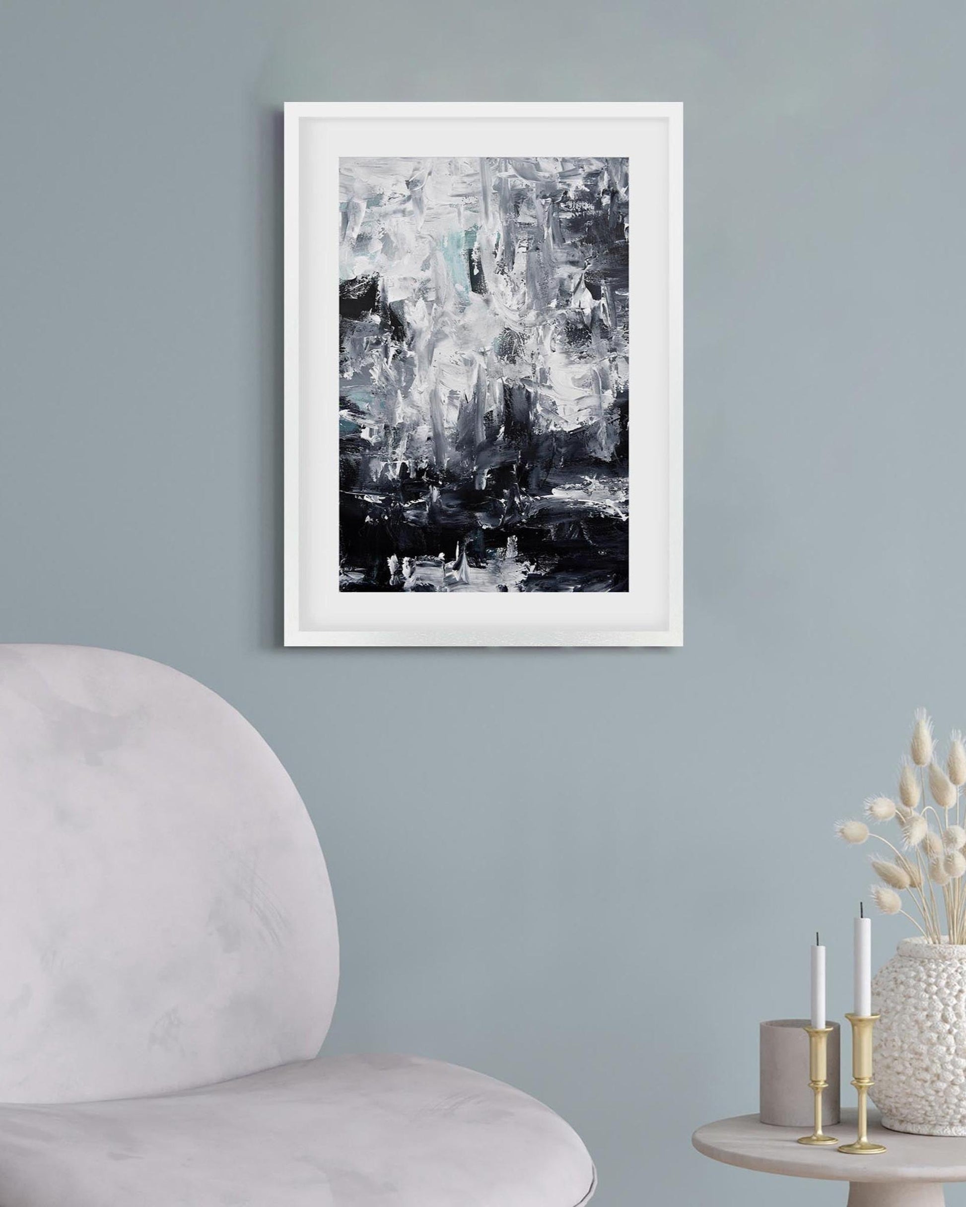 Framed abstract art on a gray wall with a modern chair and decorative items.