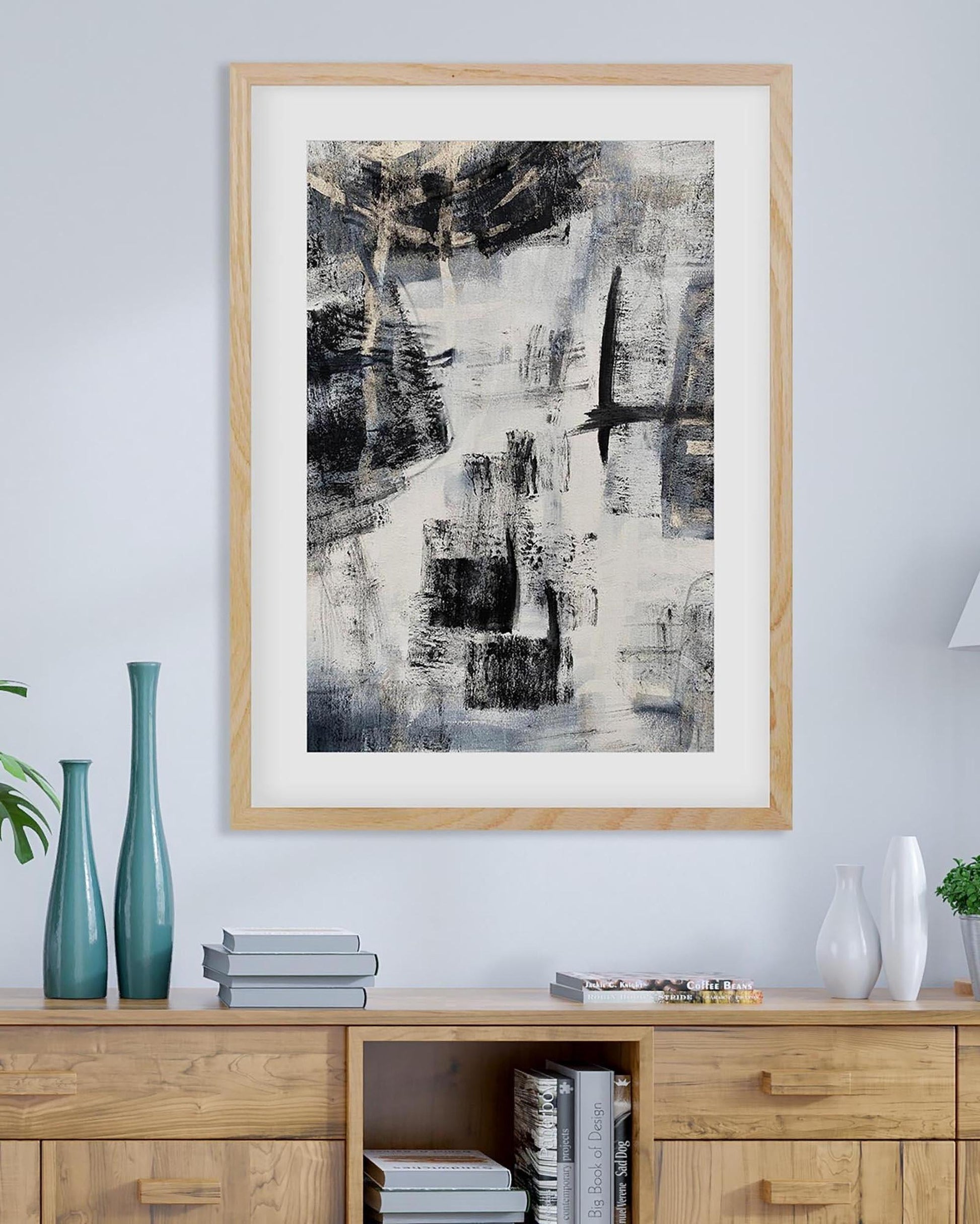 Abstract art print in a wooden frame on a wall above a wooden cabinet.
