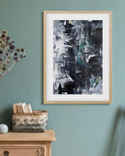 Framed abstract art on a wall with a vase of dried flowers and a basket below.