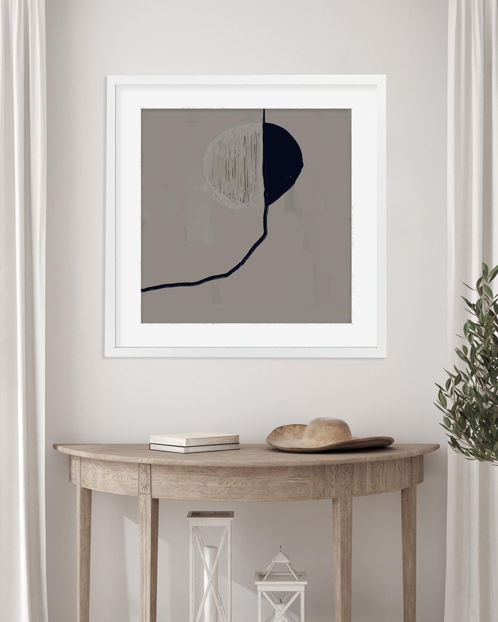 Framed abstract art on a wall above a wooden console table with decor items.