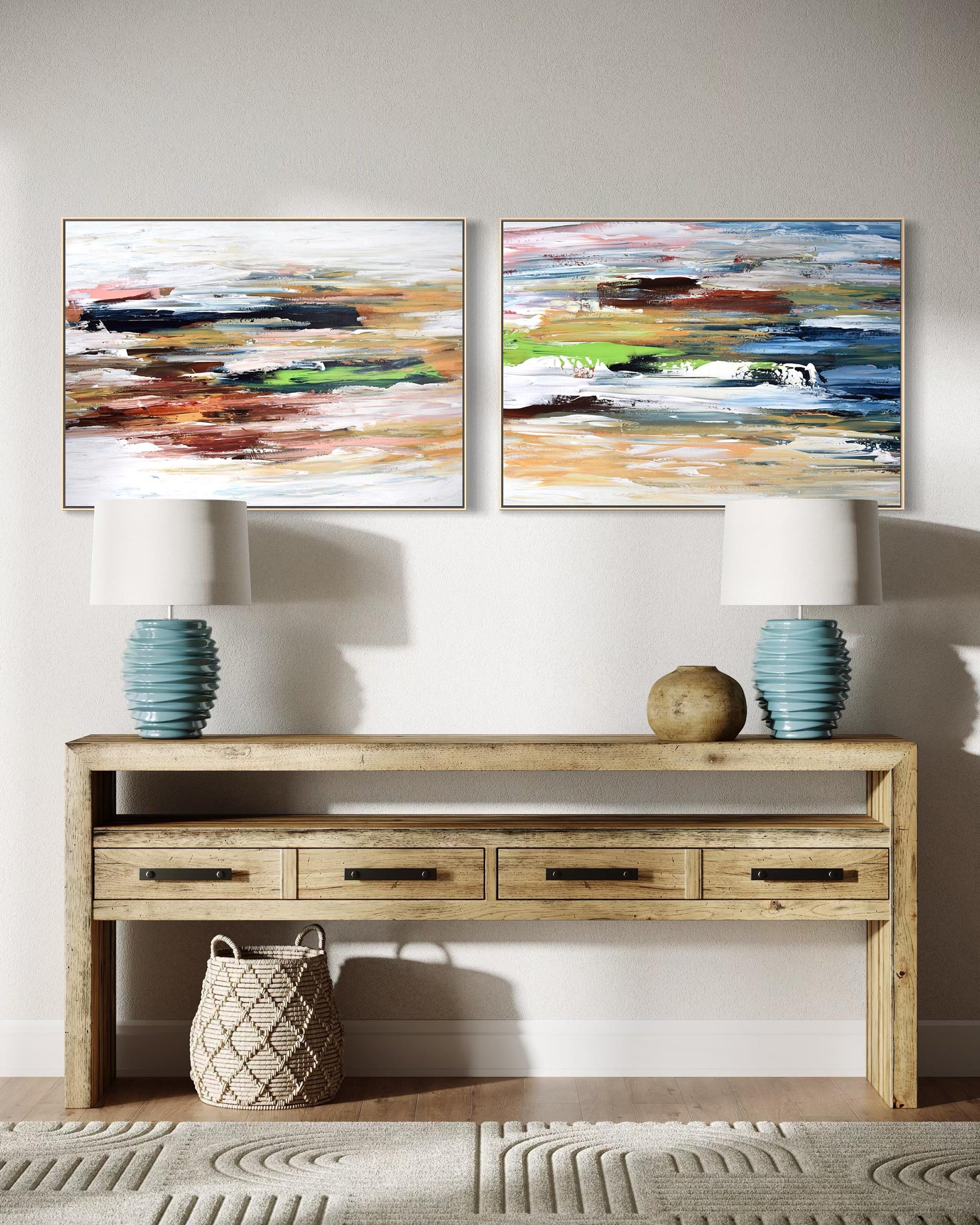 Two abstract paintings above a wooden console table with lamps and decor items.
